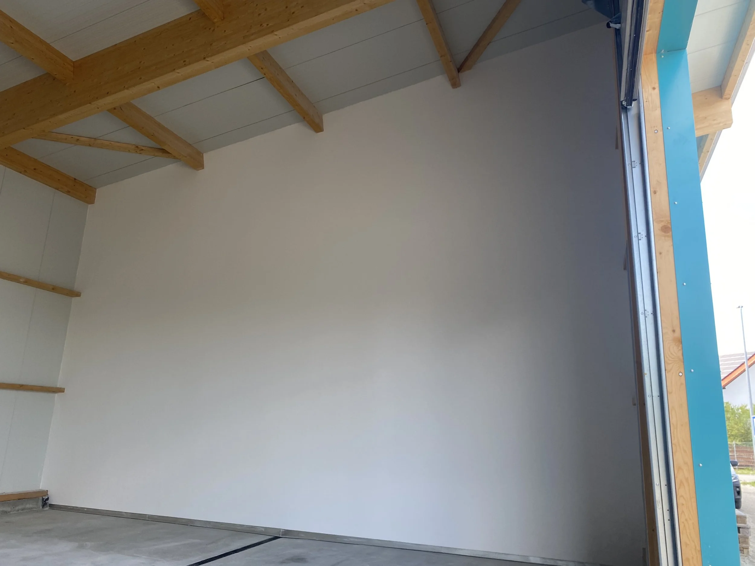 Innenansicht eines unfertigen Garagentors mit Holzrahmen, weißen Wänden und Holzdecke