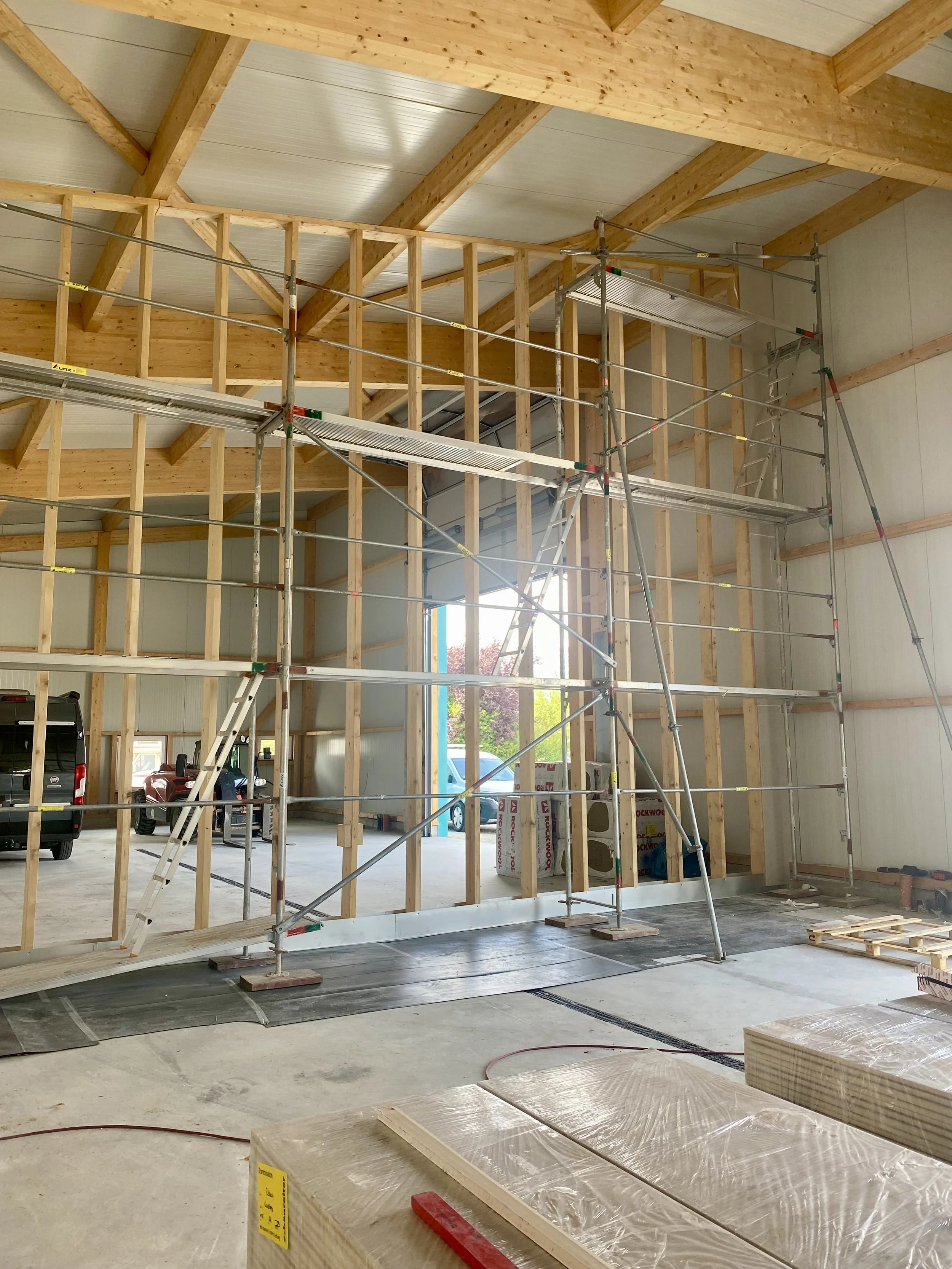 Baugerüst in einem Holzbau mit sichtbaren Holzwänden und -decken in einem Gebäude im Bau.