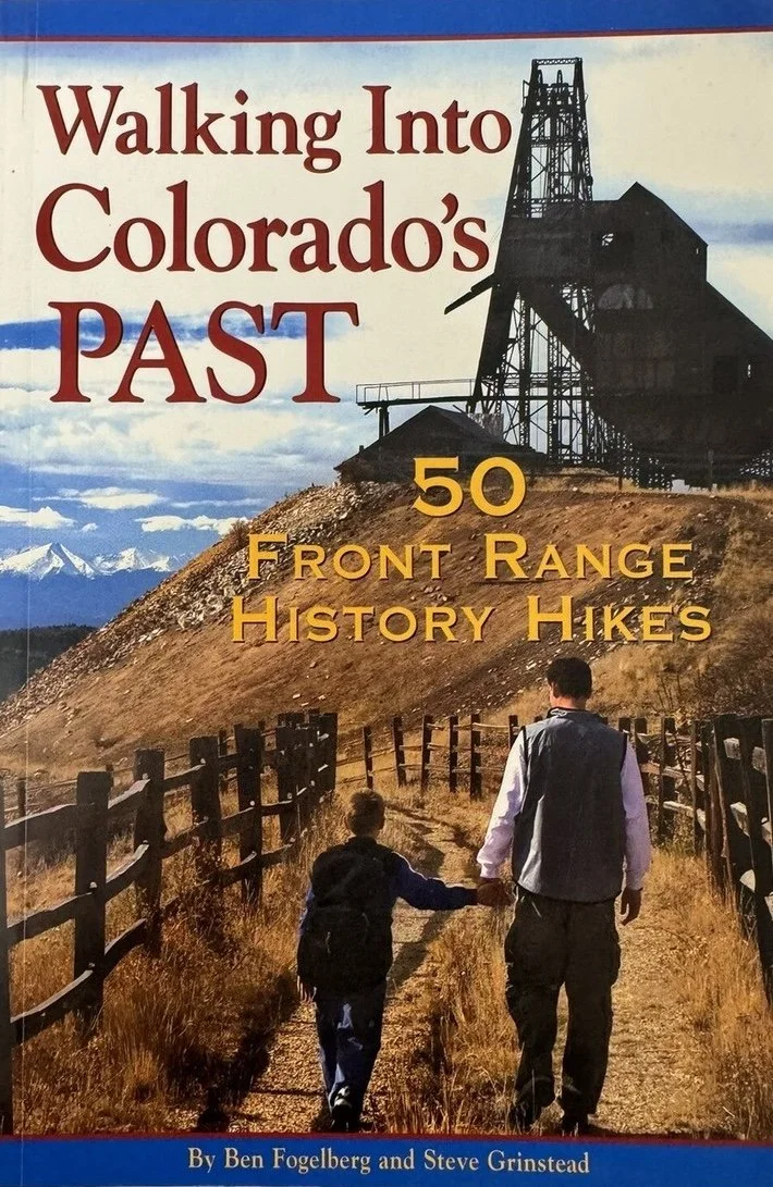 Cover of a book titled 'Walking Into Colorado's Past' with a subtitle '50 Front Range History Hikes' by Ben Fogelberg and Steve Grinstead. The cover features a photo of a man and a child walking on a dirt trail along a fence line, towards an old mine structure on a hill, with mountains in the background.