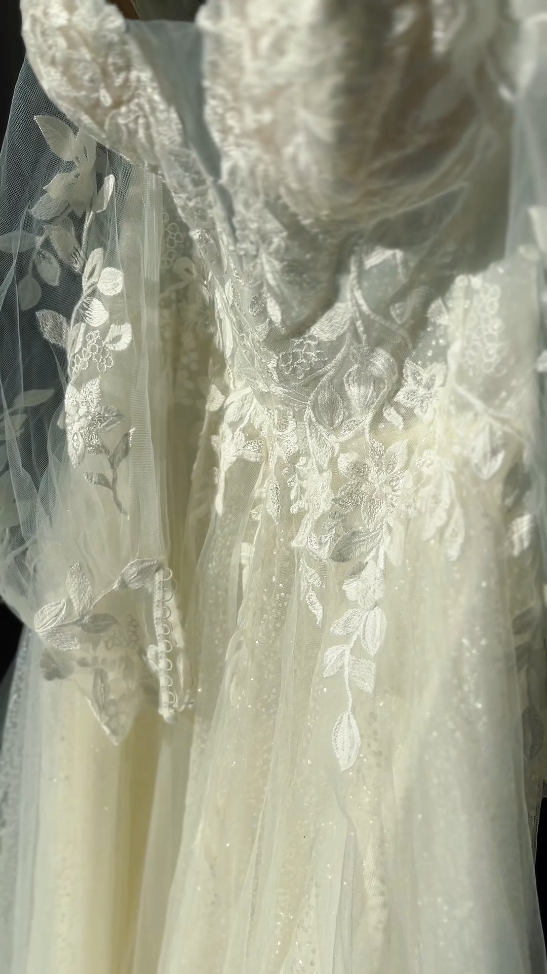 Close-up of a white wedding dress with floral lace embroidery and tulle fabric.
