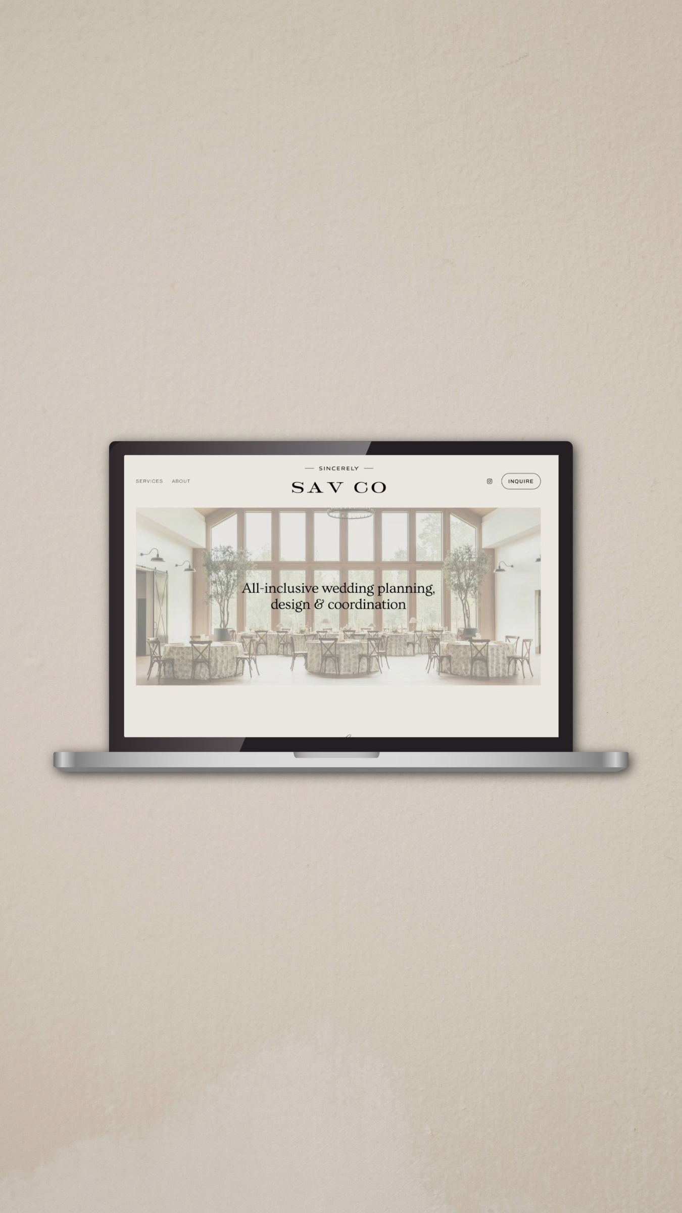 A laptop mounted on a wall displaying a website for wedding planning and coordination services, with a background image of a bright, elegant event space filled with tables and large windows.