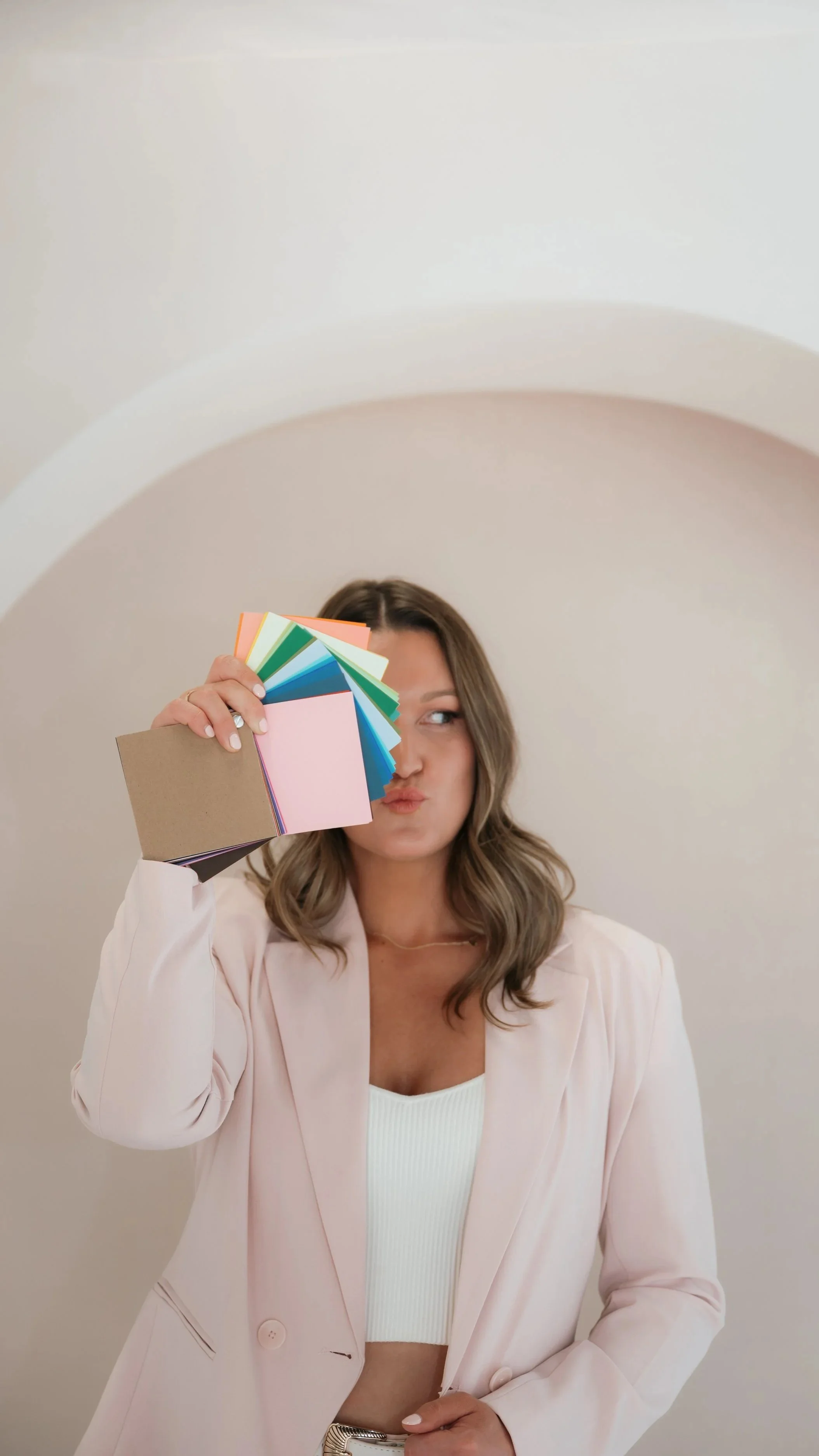Woman holding a color swatch fan while making a pouting face.
