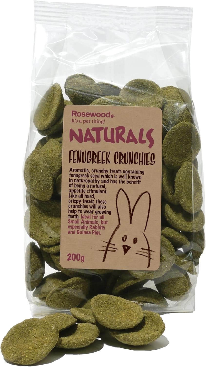 A clear plastic bag containing green fenugreek crunchie treats with a pink label featuring a bunny drawing. The label states the treats are aromatic, crunchy, made with fenugreek seed, and suitable for small animals, especially rabbits and guinea pigs.