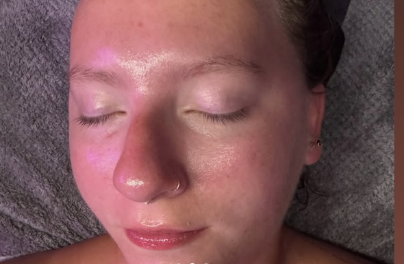 A person with a nose ring resting with eyes closed on a gray towel.