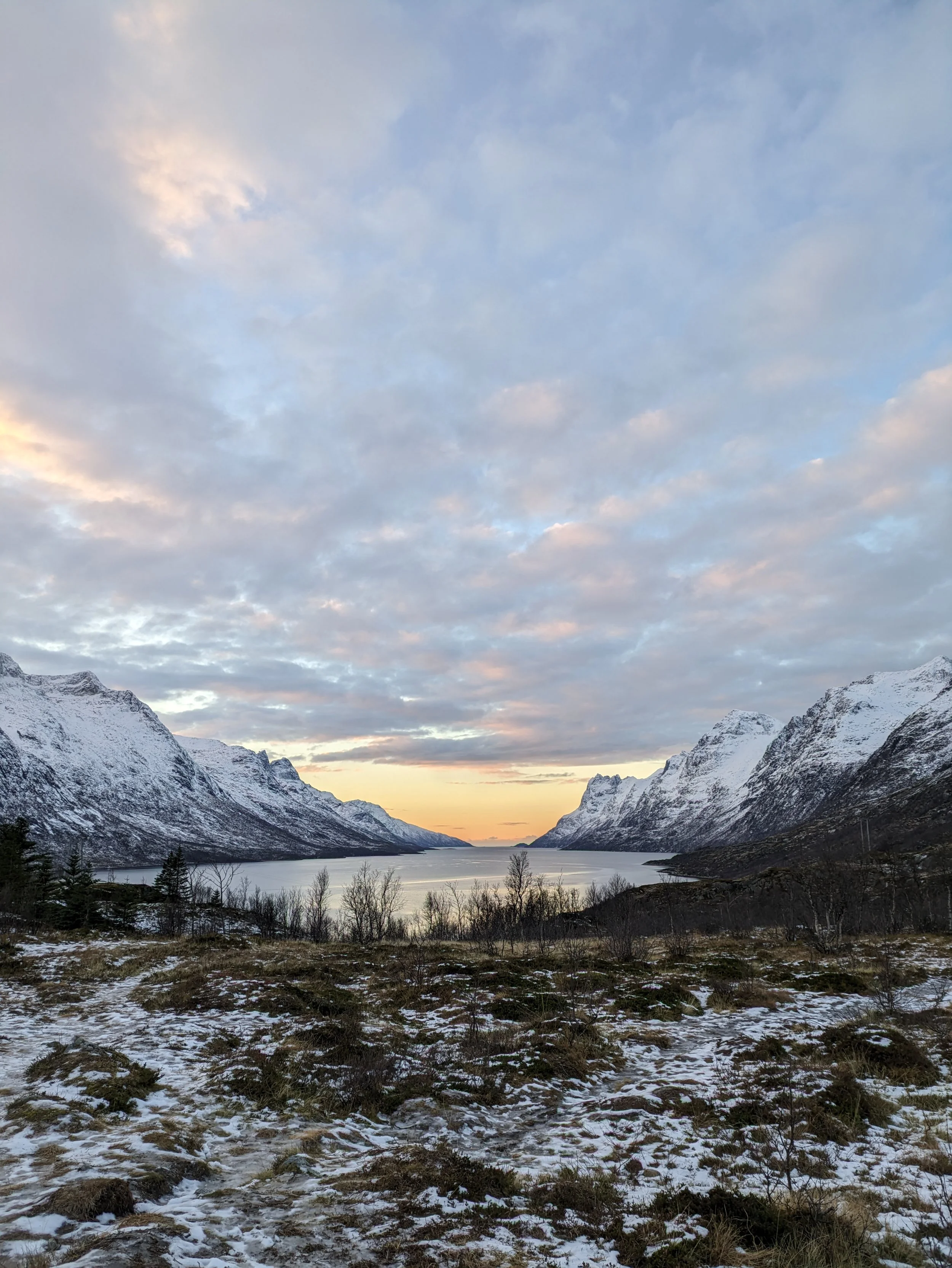 A beautiful view of a Norwegian fjord in the winter. The snow-covered mountains and calm water are a perfect sight.