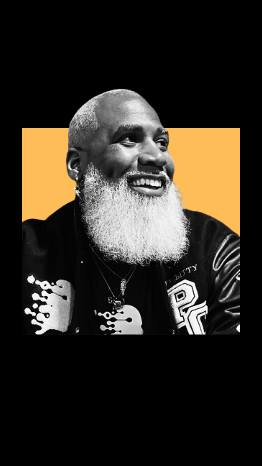 A smiling Black man with a shaved head and a long white beard, wearing a black jacket with patches, against a black and yellow background.