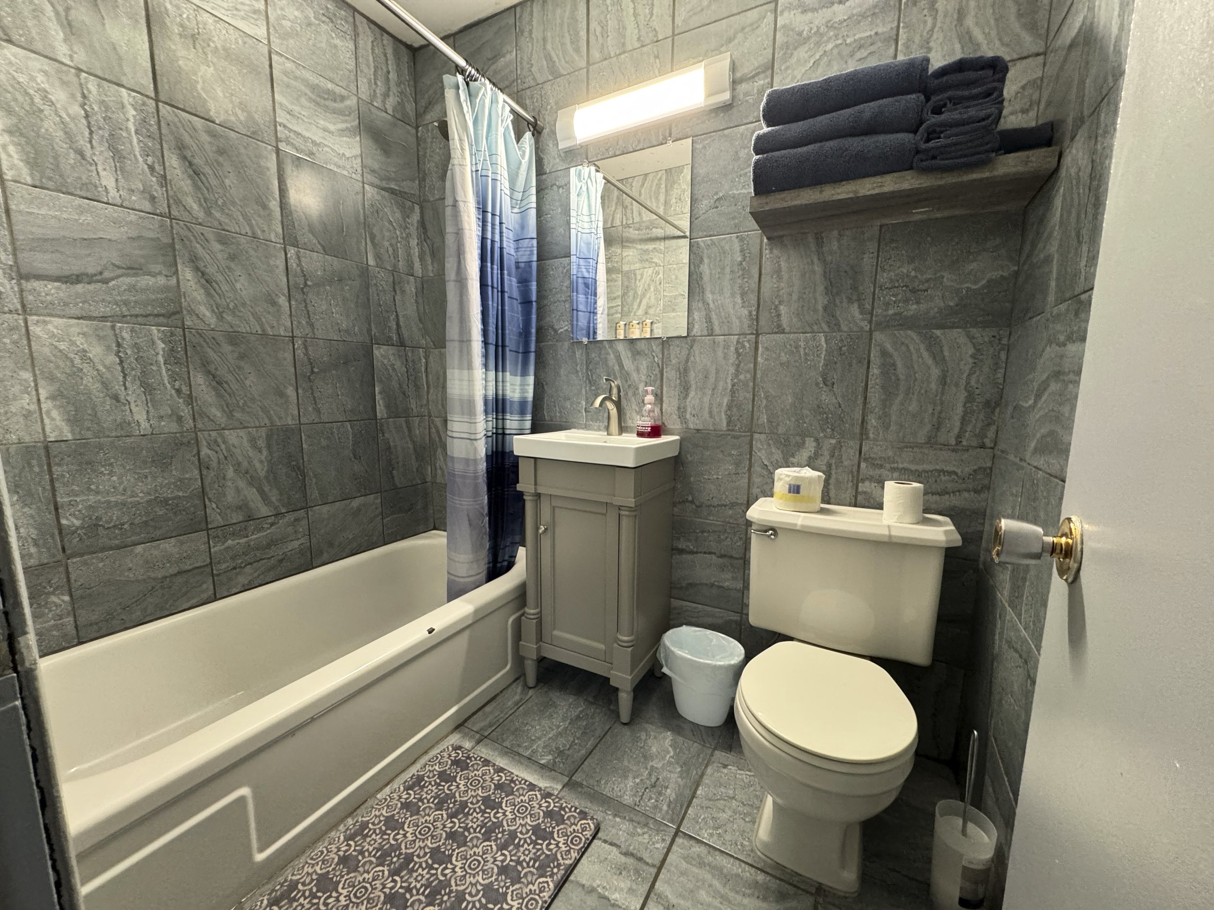 Newly remodeled tiled bathroom with high-quality linens and full tub with shower.