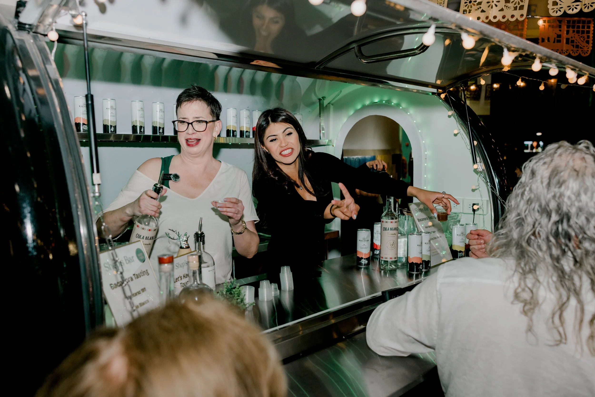 Shep and a fellow host welcoming guests at a spirits tasting inside the mobile bar trailer.