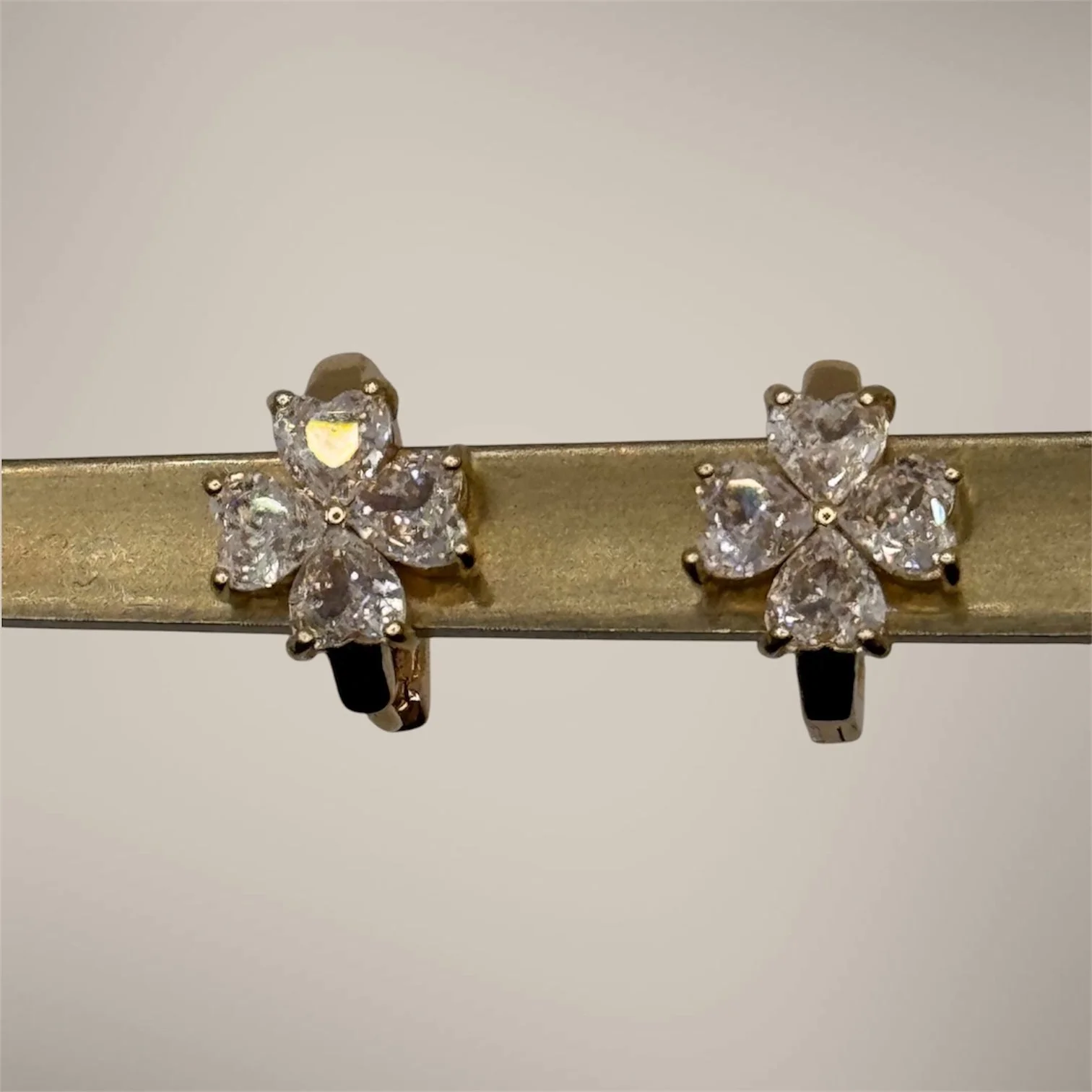 Pair of earrings shaped like butterfly clusters with clear stones, displayed on a metallic stand.