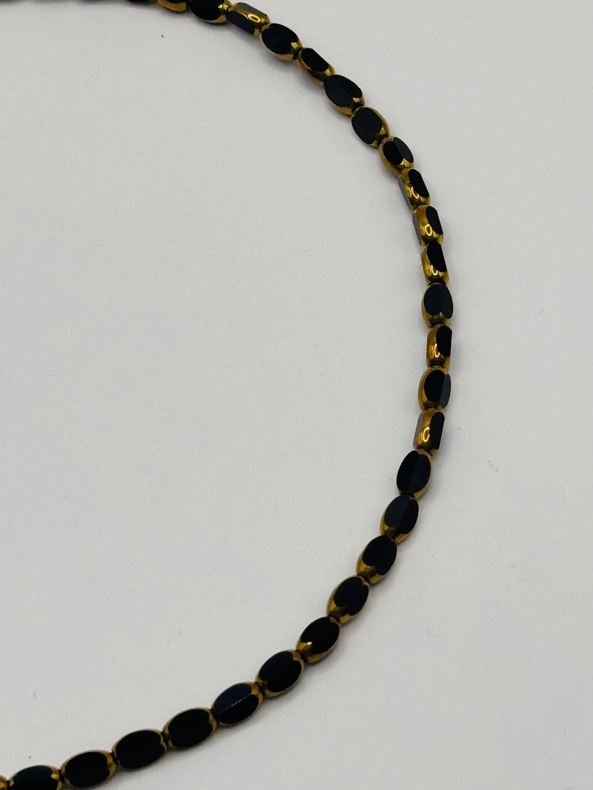 A gold and black beaded necklace against a white background.