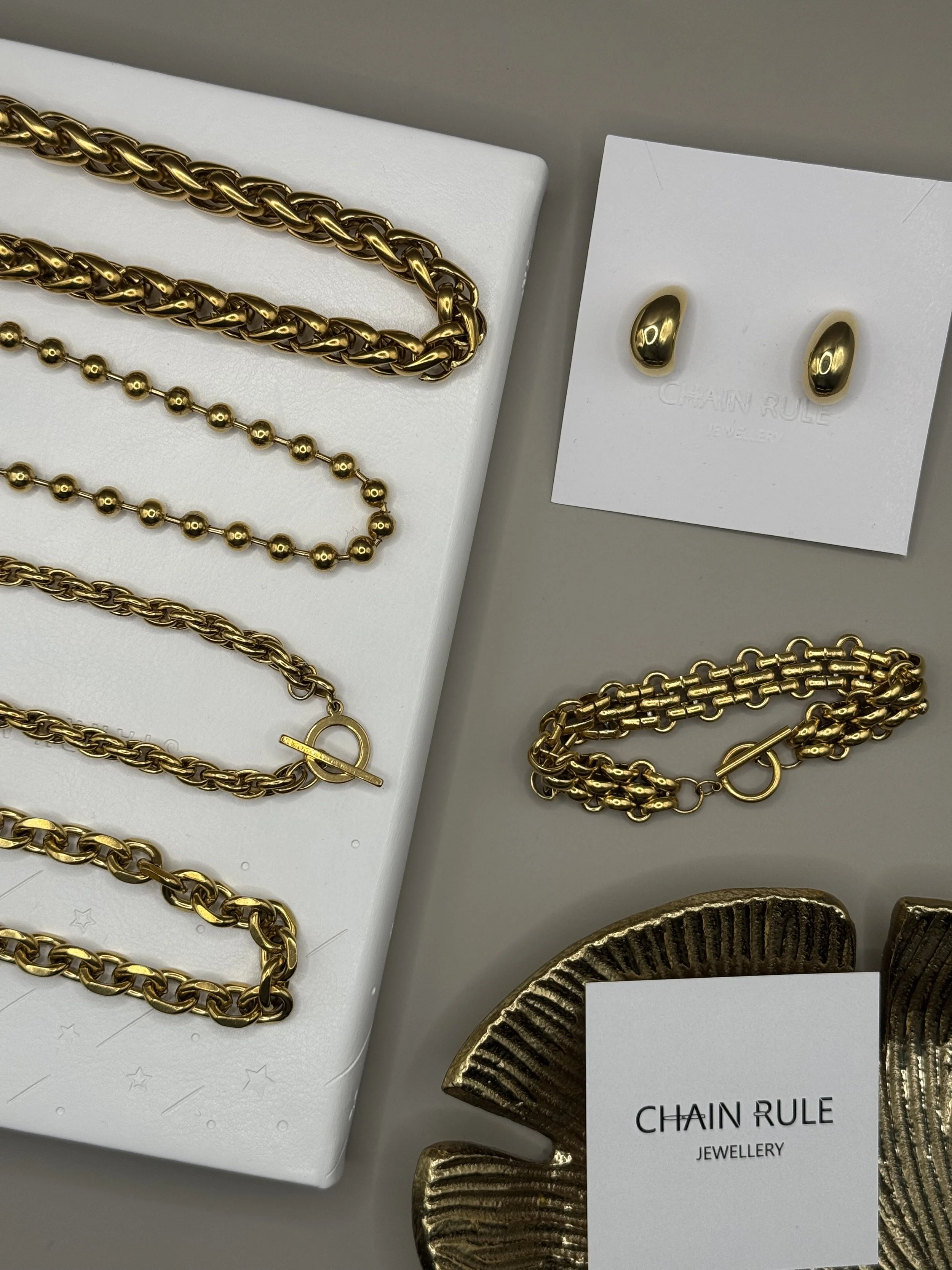 Several gold  chains laid on a lime green surface with shadows.