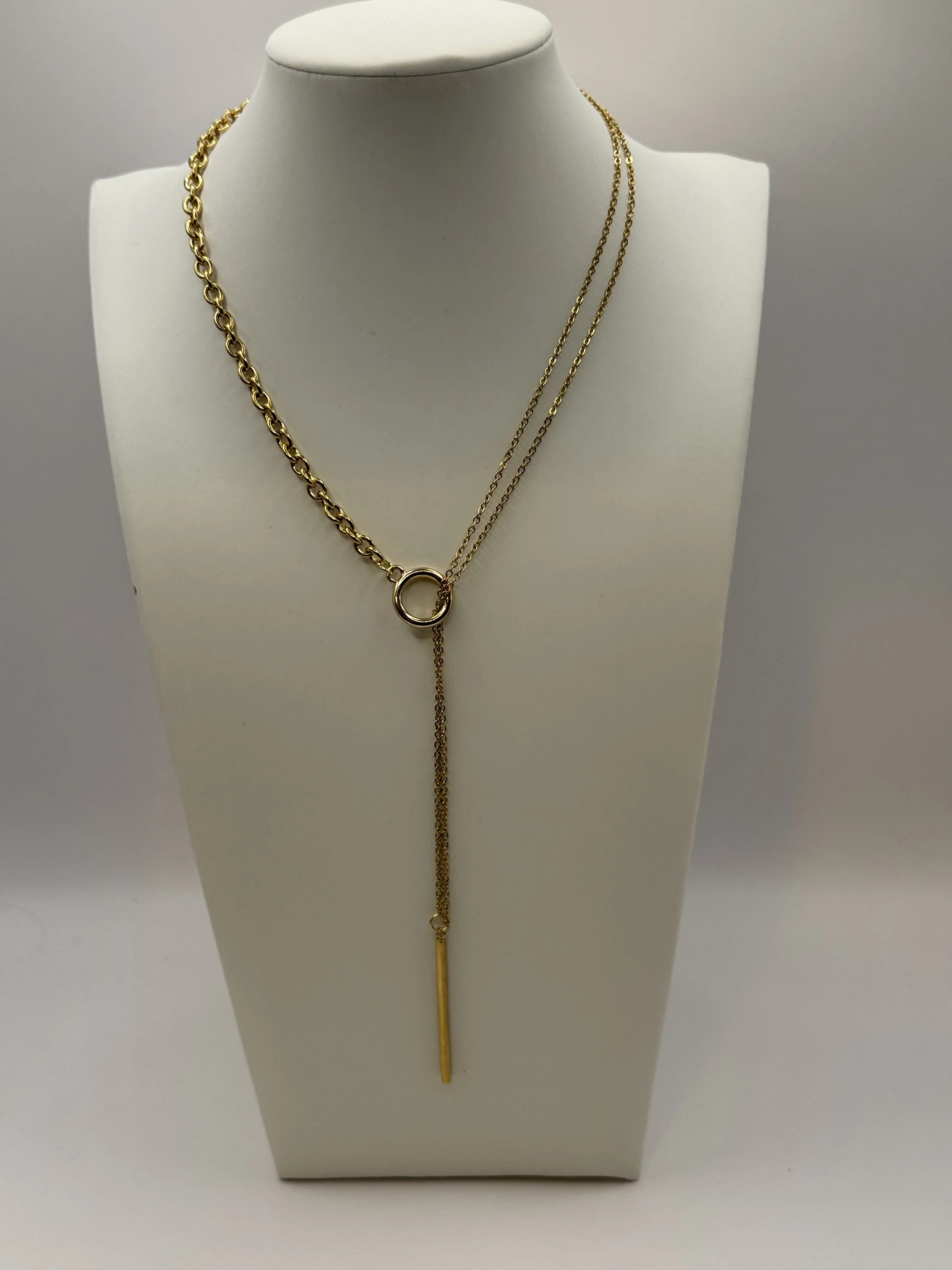 Gold layered necklace with chain links, a ring pendant, and a long vertical bar pendant displayed on a white jewellery bust. This is Chain Rule Jewellery's PM/Luna necklace.