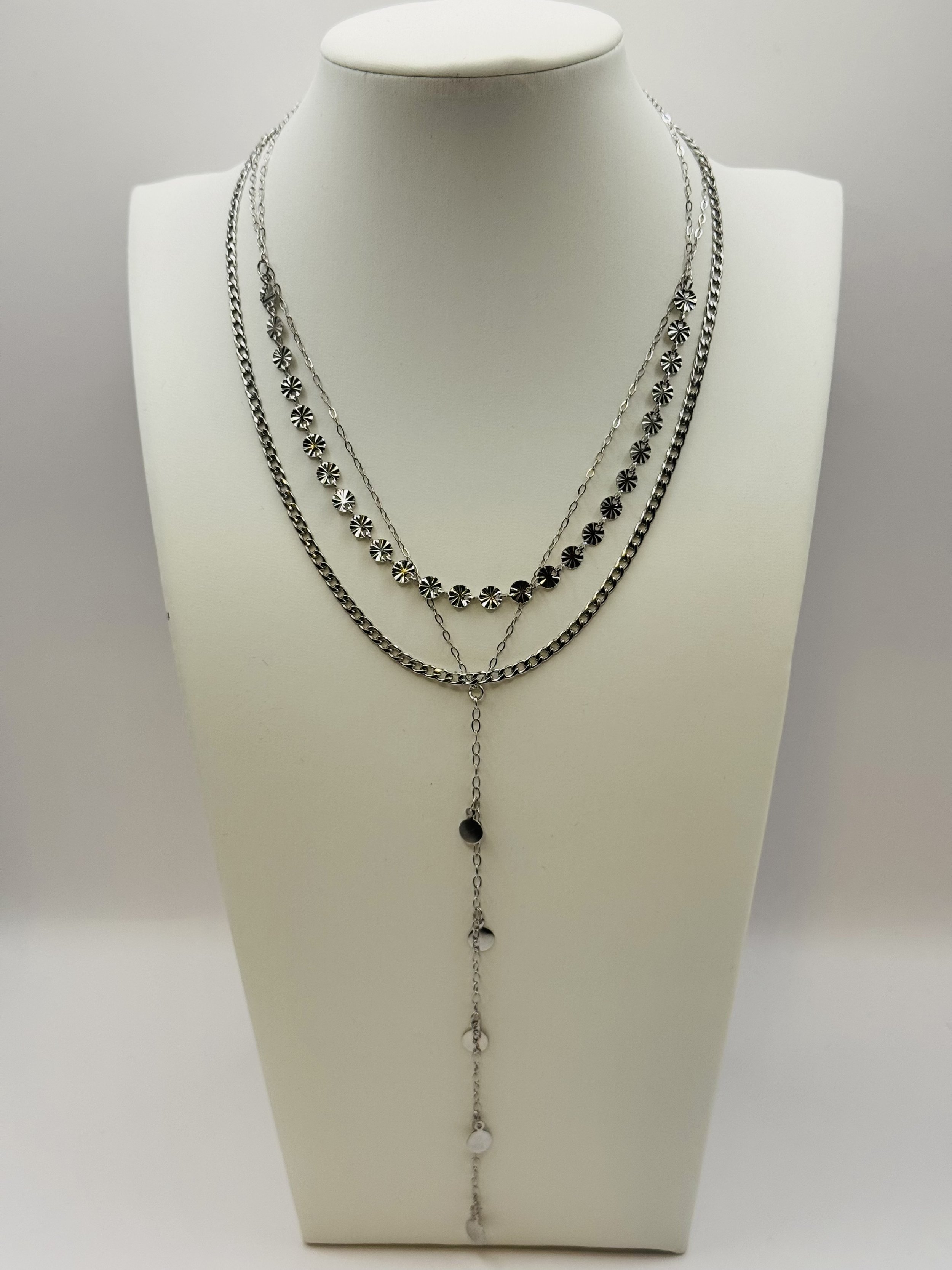 Three layered silver necklaces with various chain designs and decorative elements displayed on a white bust