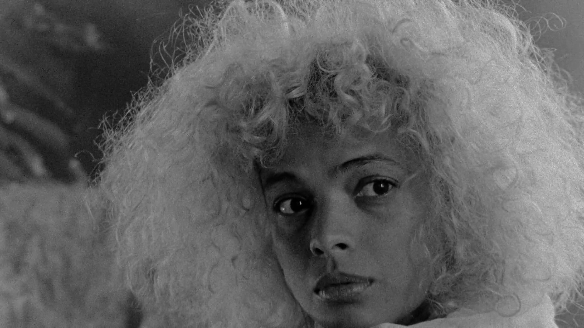 black and white image of a young woman looking towards the camera, shot on 16 mm analog film