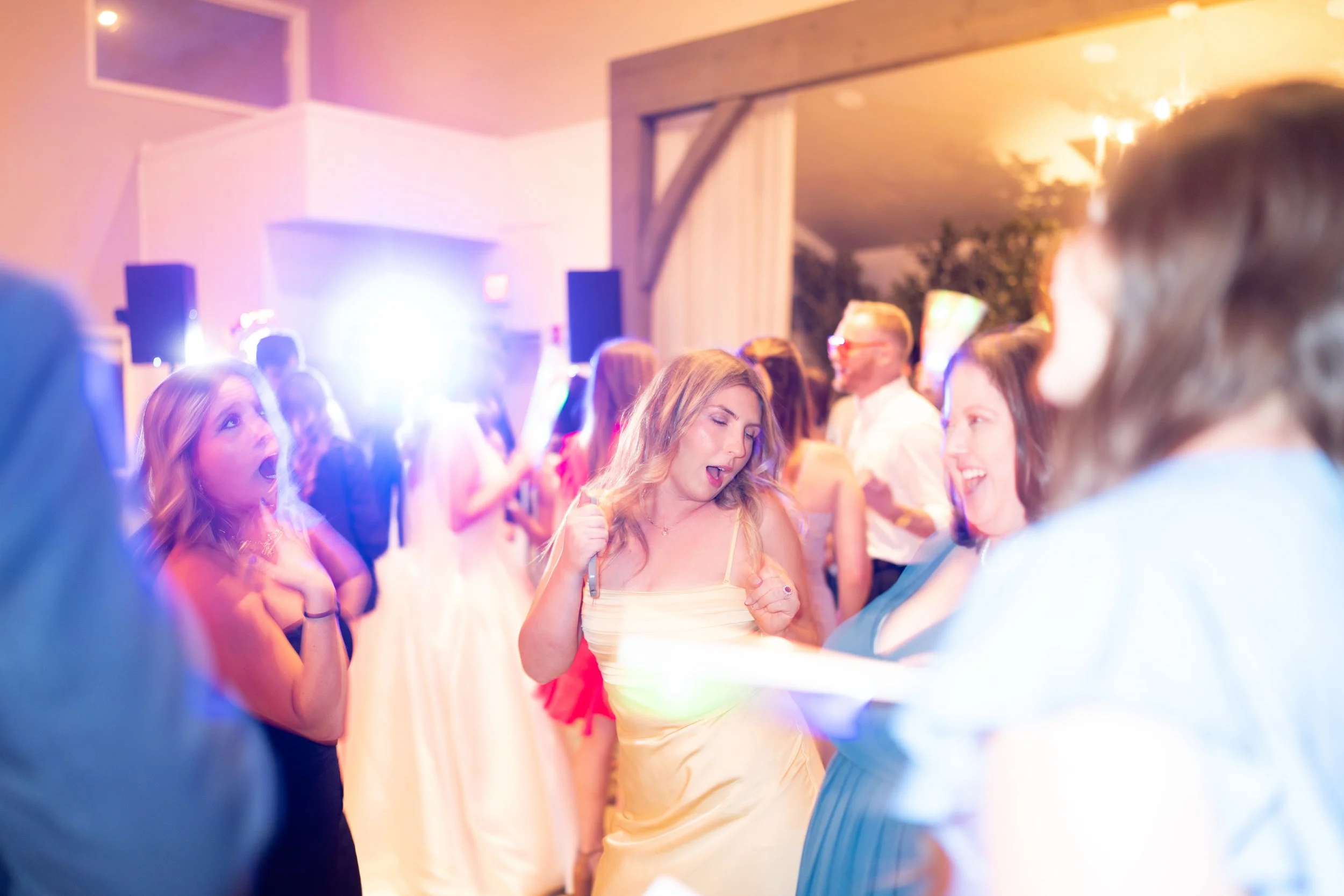Wedding reception photos. People dancing and enjoying themselves at a lively party with colorful lighting.