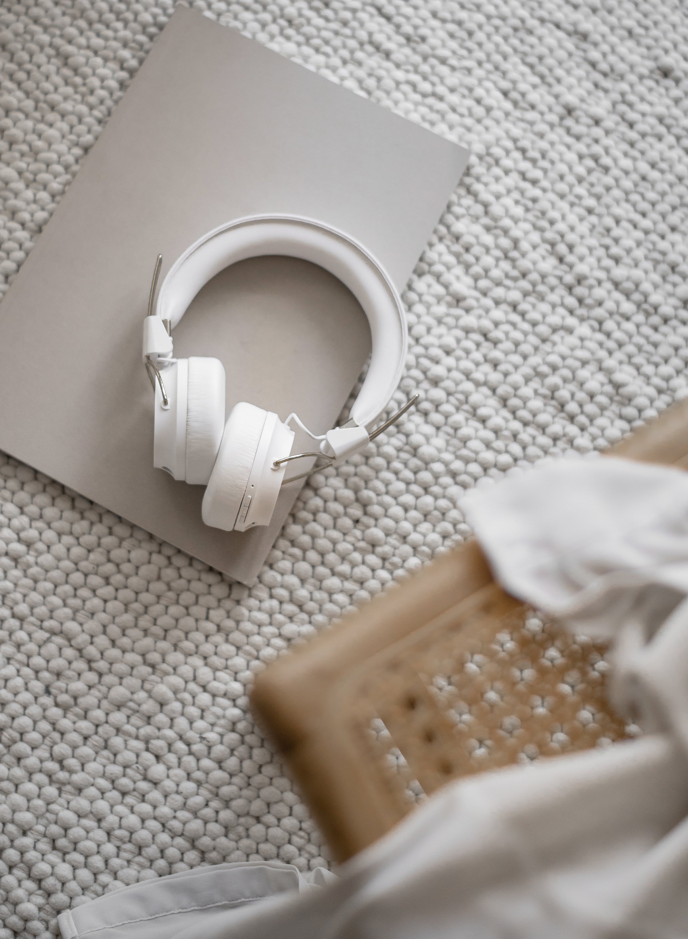 White headphones resting on a beige box on a textured white surface.
