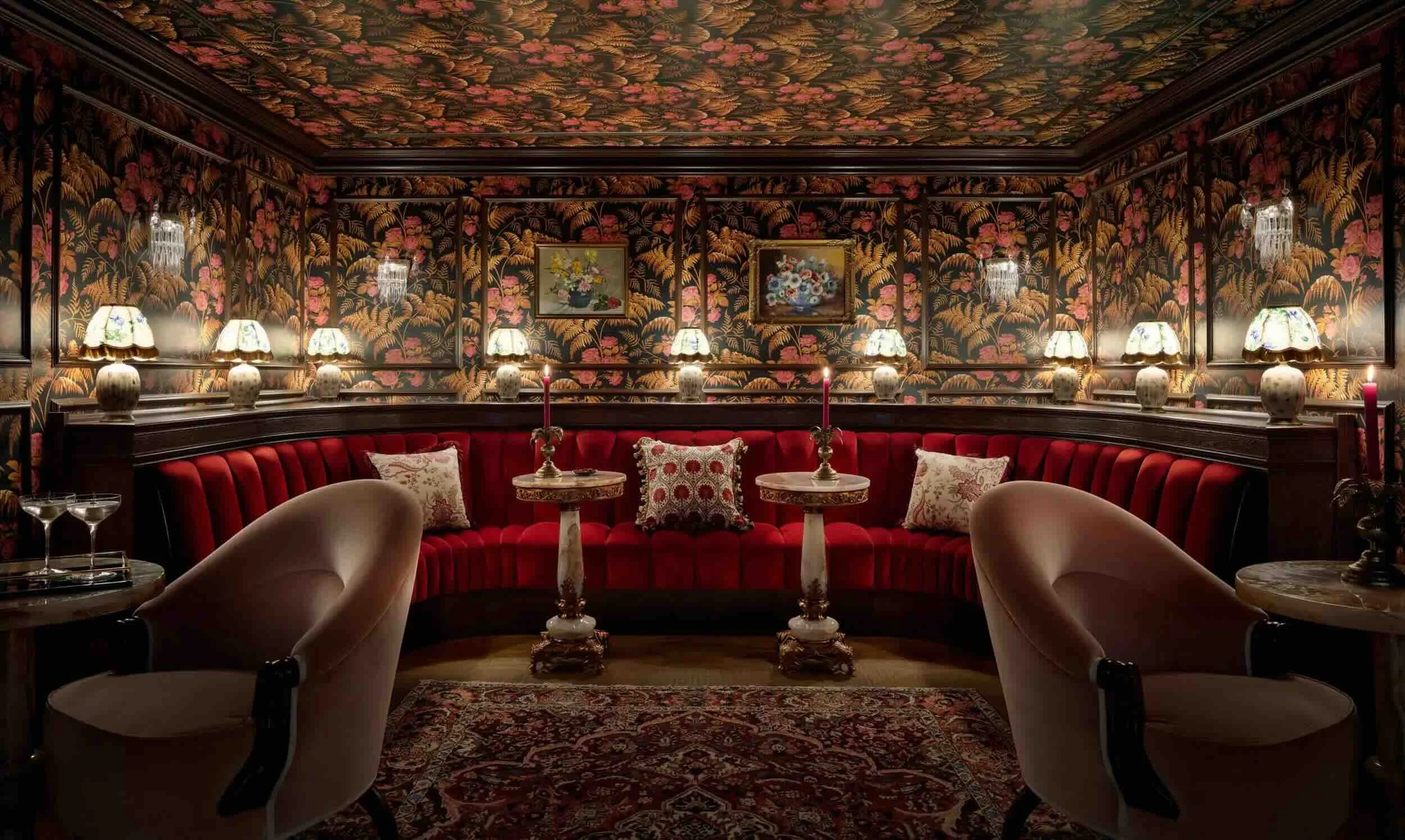 Lounge-style seating at a competitive socialising venue, featuring floral wallpaper, red banquettes and decorative lighting