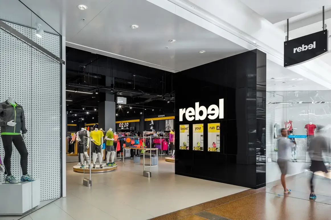 Rebel Sport retail interior with illuminated signage, open display racks and bold black finishes — interior design by Studio Hayes