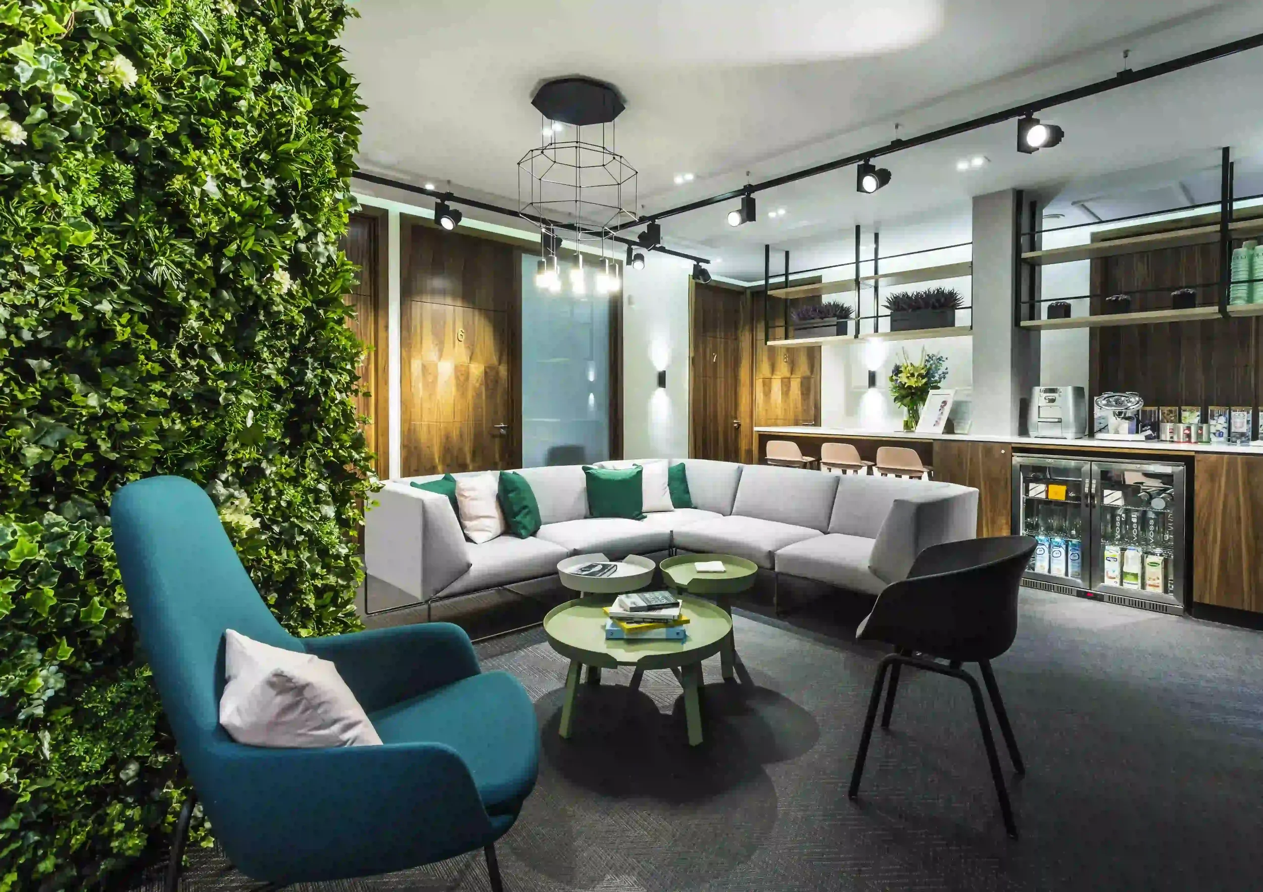 Eudelo Clinic lounge with green living wall, modular sofa and contemporary lighting — interior design by Studio Hayes