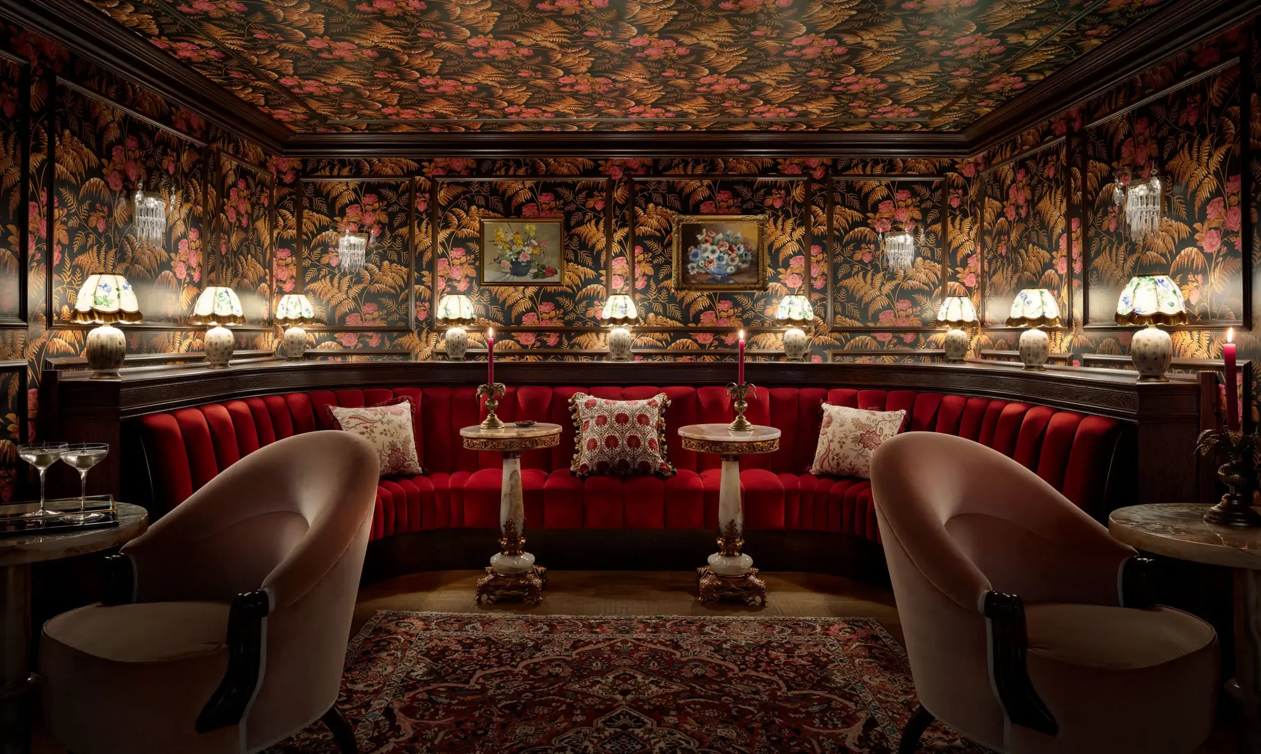Graduate Cambridge lounge with floral wallpaper, red curved seating and decorative lamps — interior design by Studio Hayes