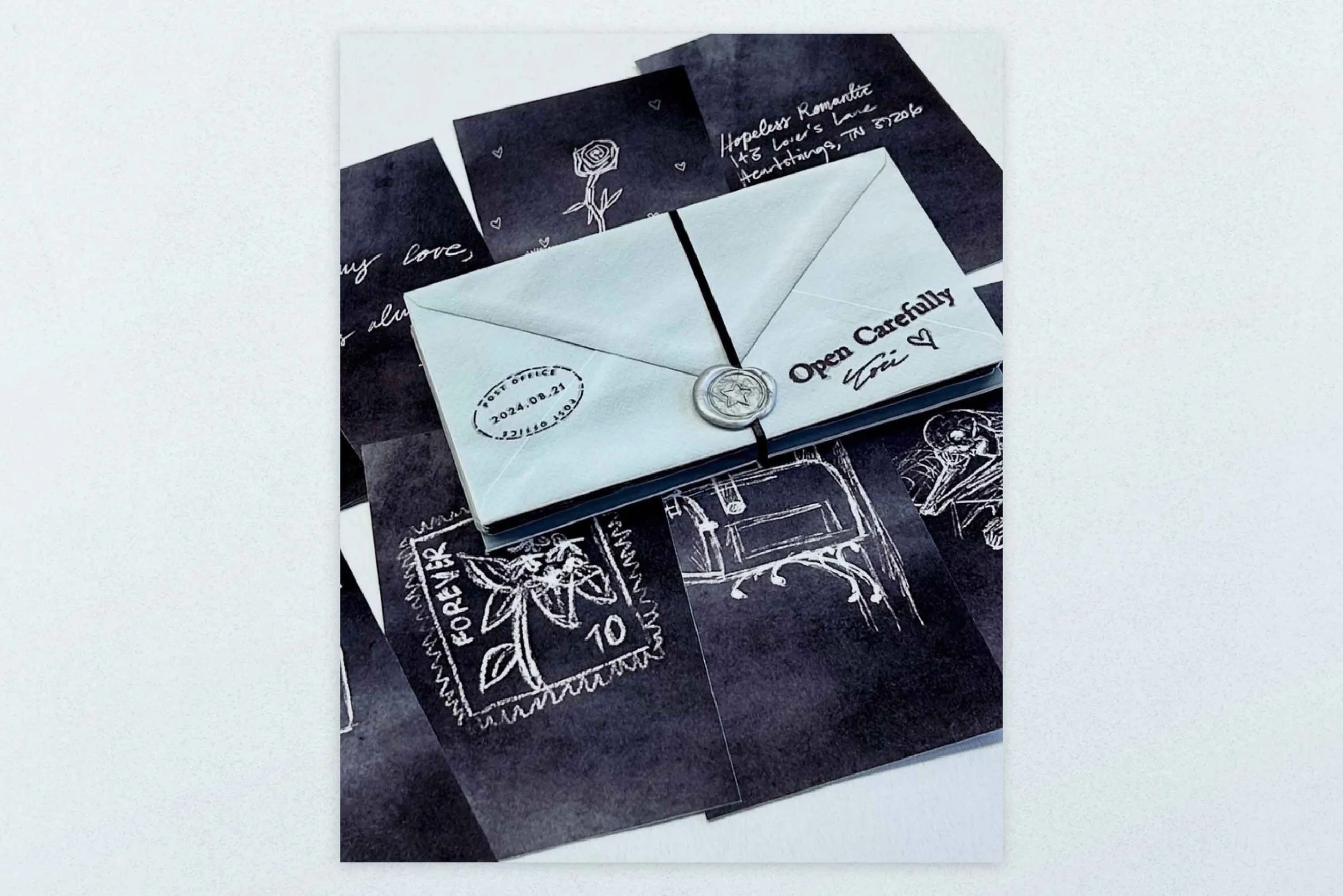 A white paper envelope with the words "Open Carefully" and a signature, sealed with a decorative wax seal, resting on a black and white illustrated background with drawings of a rose, a handwriting note, a postage stamp, and a vintage chair.