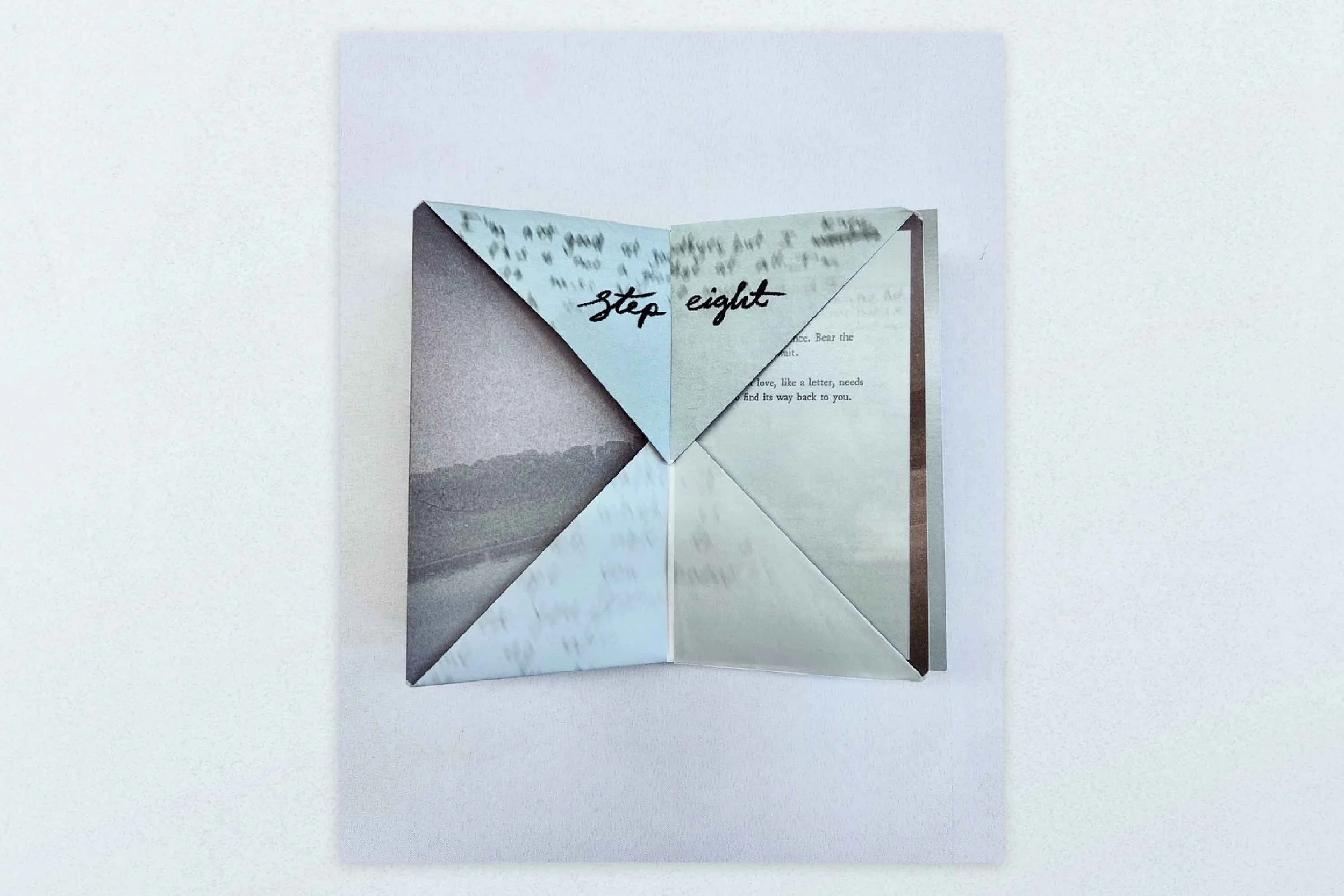 A paper fold-out card with an origami design and a handwritten note that reads 'step eight' in black ink.