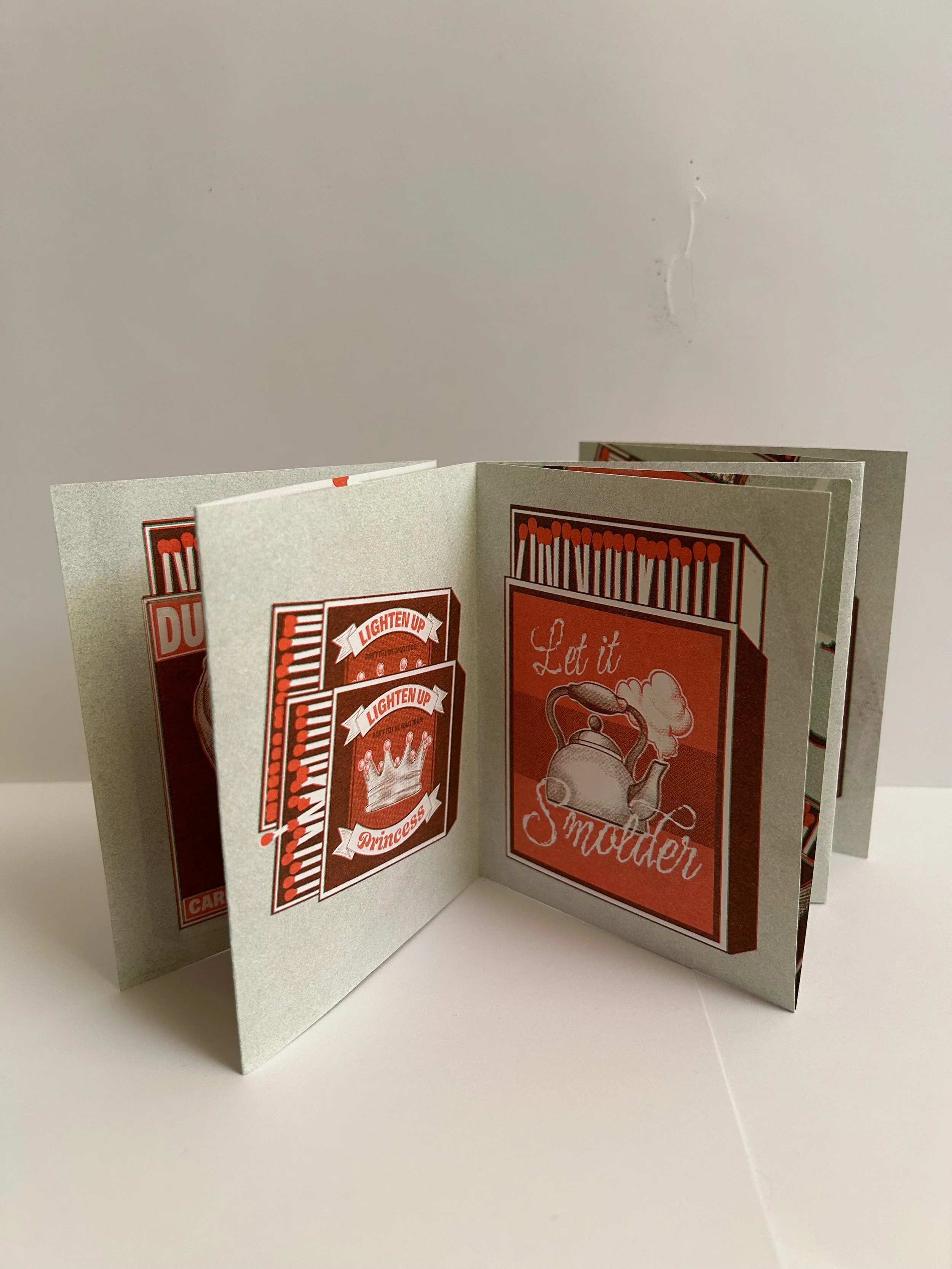 Silver foldable paper greeting card with red, white, and gray designs and text, featuring a teapot with steam and a crown with the words "LIGHTEN UP PRINCESS" and "Let it Sprinkle".