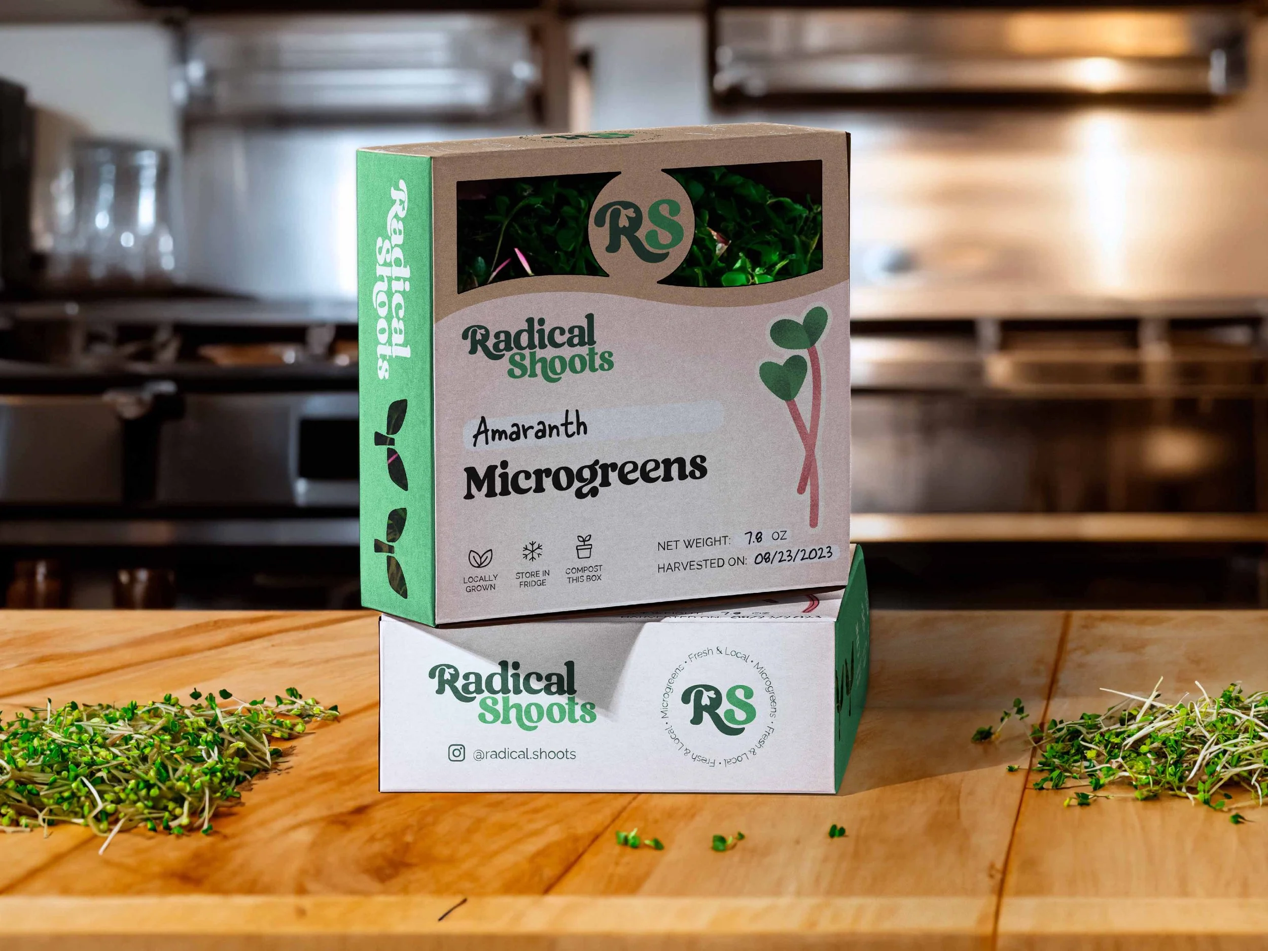 Box of Radical Shoots microgreens labeled as Amaranth microgreens on a wooden surface with loose microgreens scattered nearby.