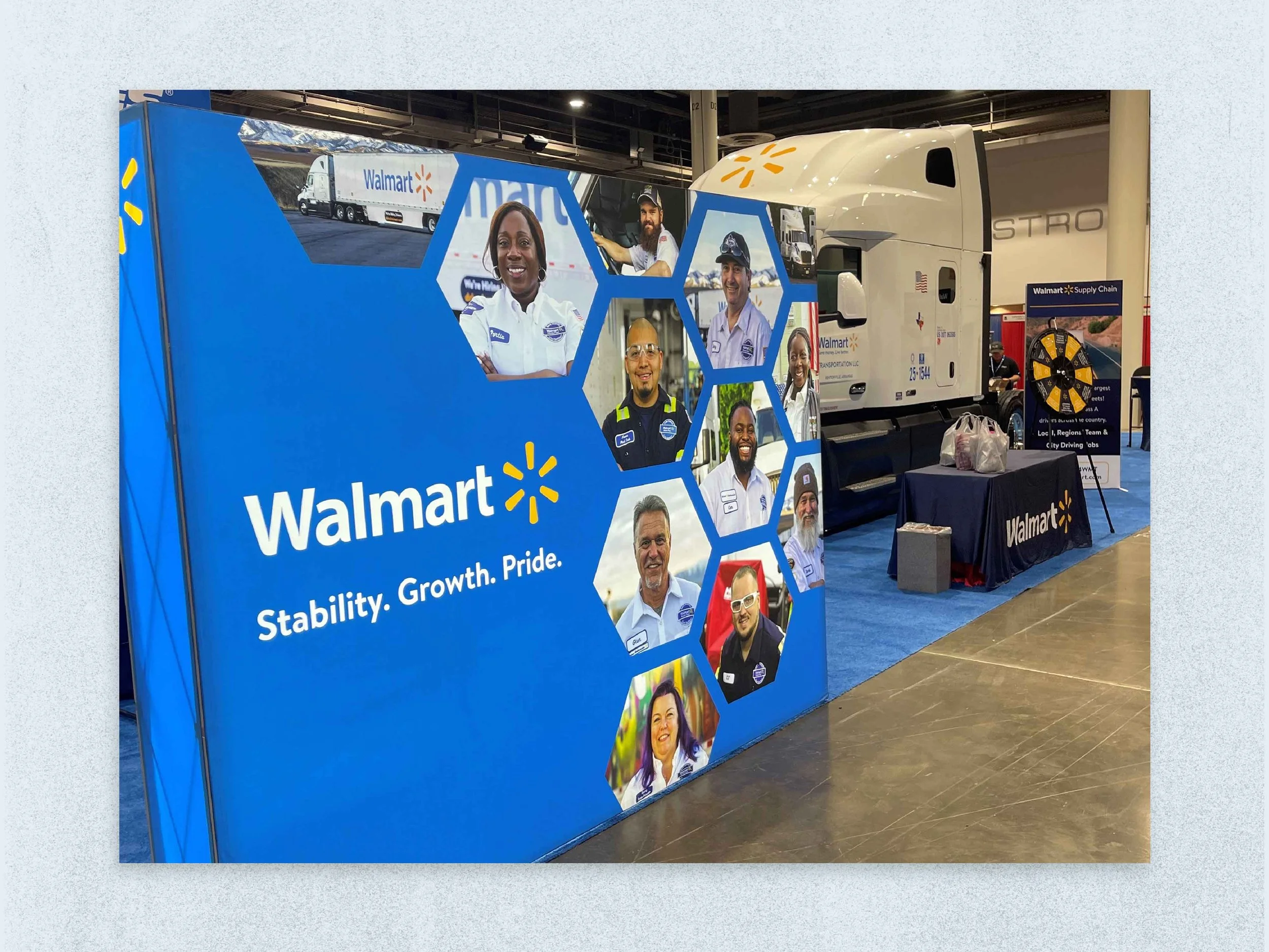 Walmart display booth featuring the slogan "Stability. Growth. Pride." with photos of Walmart employees, a truck, and a table with Walmart-branded materials at an indoor event.