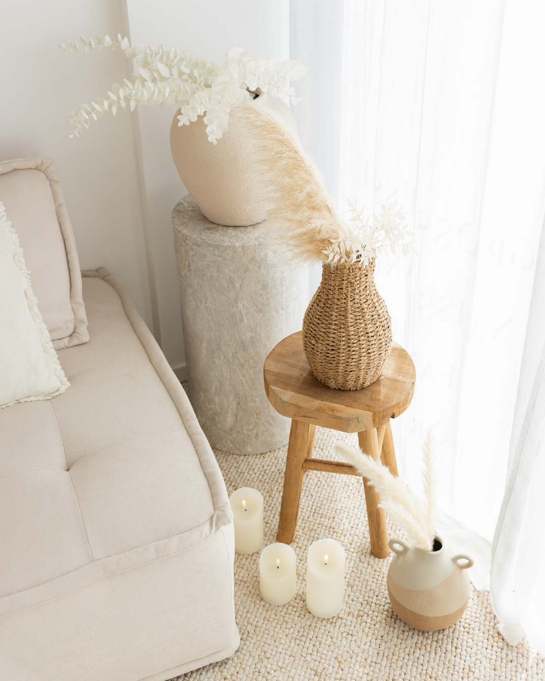 Décor intérieur avec des vases, des bougies et des coussins dans un style neutre et épuré.