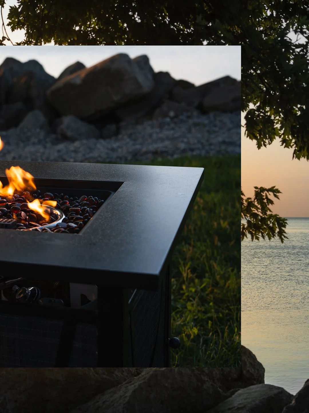 Fire pit with flames and stones, outdoor setting near water at sunset