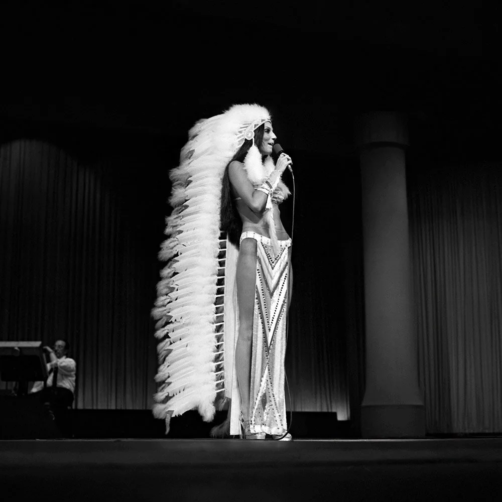 Cher — "The Headdress," CNE Grandstand, Toronto, September 1, 1973. This is an official, previously unseen and unpublished archival print captured by John Rowlands. Documenting the genesis of the legendary Cher and Bob Mackie partnership, the image f