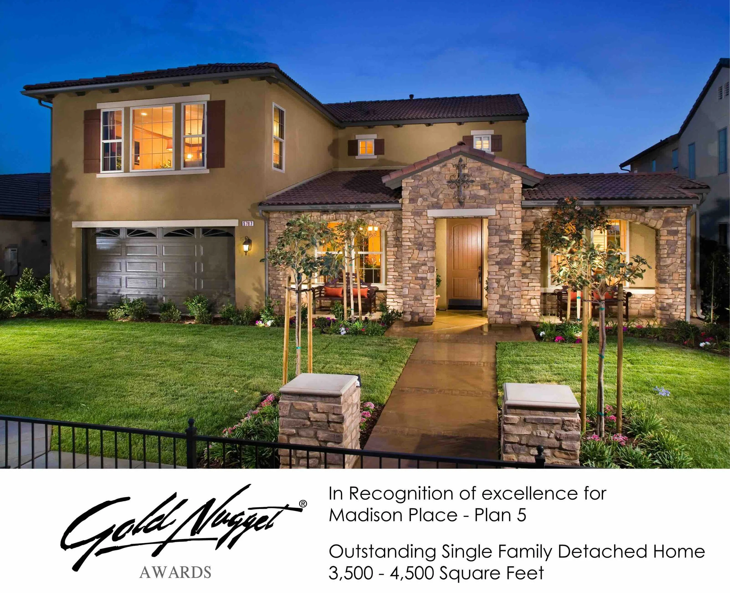 Front view of a decorated single-family detached home with well-maintained lawn, small trees, and flower beds, illuminated during evening hours, with a recognition plaque for excellence under the Gold Nugget Awards at the bottom.