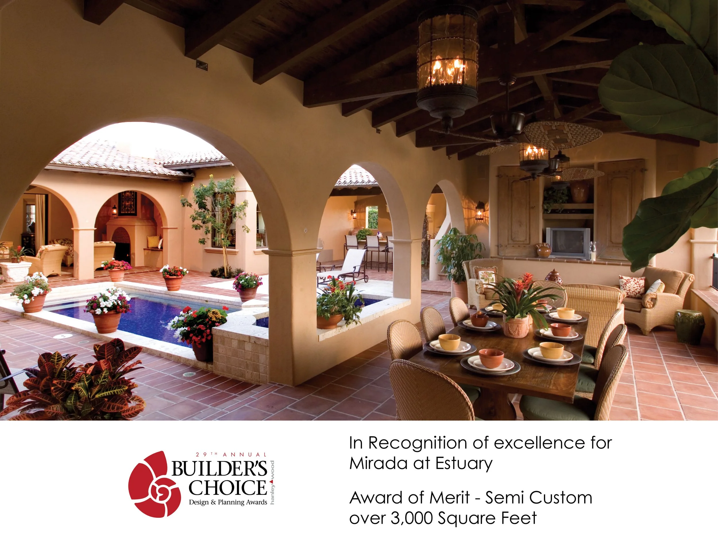 Indoor outdoor patio with a pool, potted flowers, a dining table set with dishes and a large plant, and a sitting area with chairs and a TV, part of a luxurious estate or resort.
