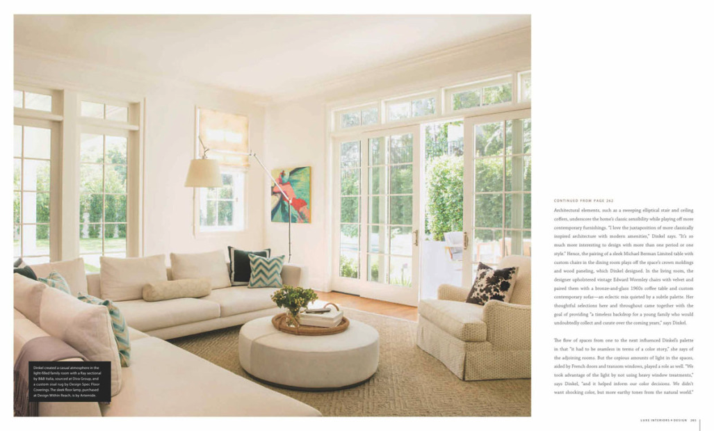 Bright living room with large windows, white sofa, coffee table, and artwork on the wall.