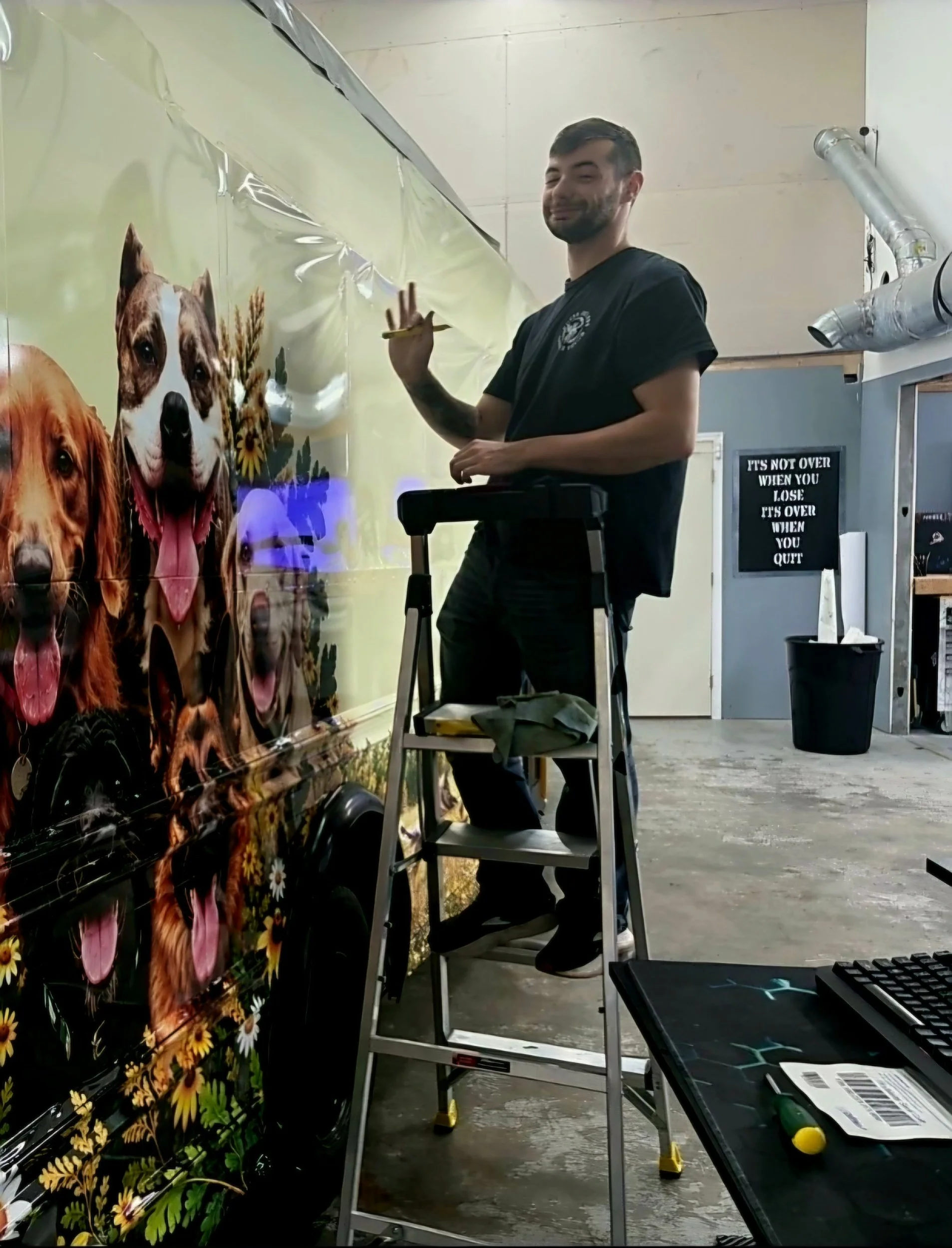 Installer on a ladder working on a wrap on a bus