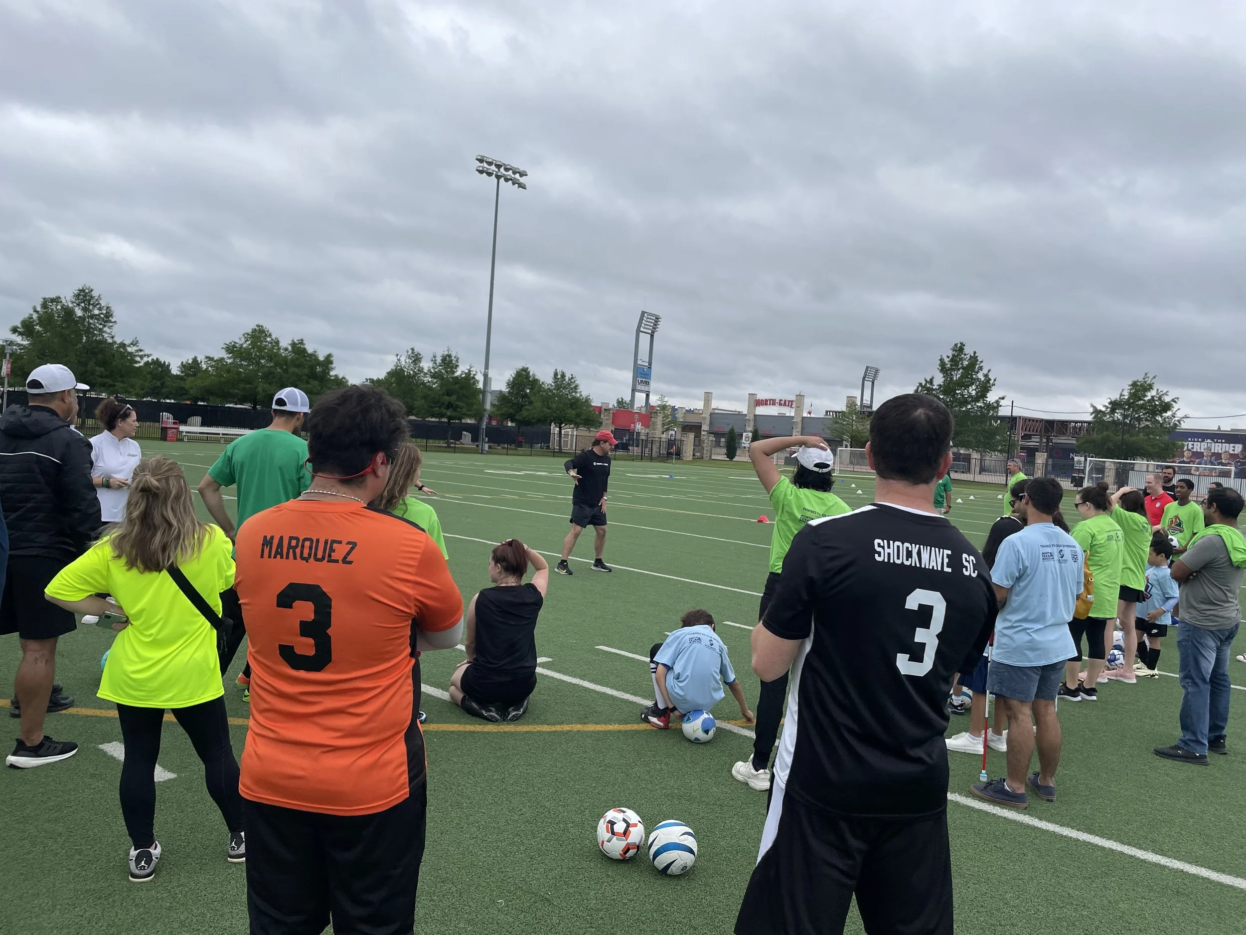 Youth soccer practice or game on a field, with players in colorful jerseys and spectators watching.