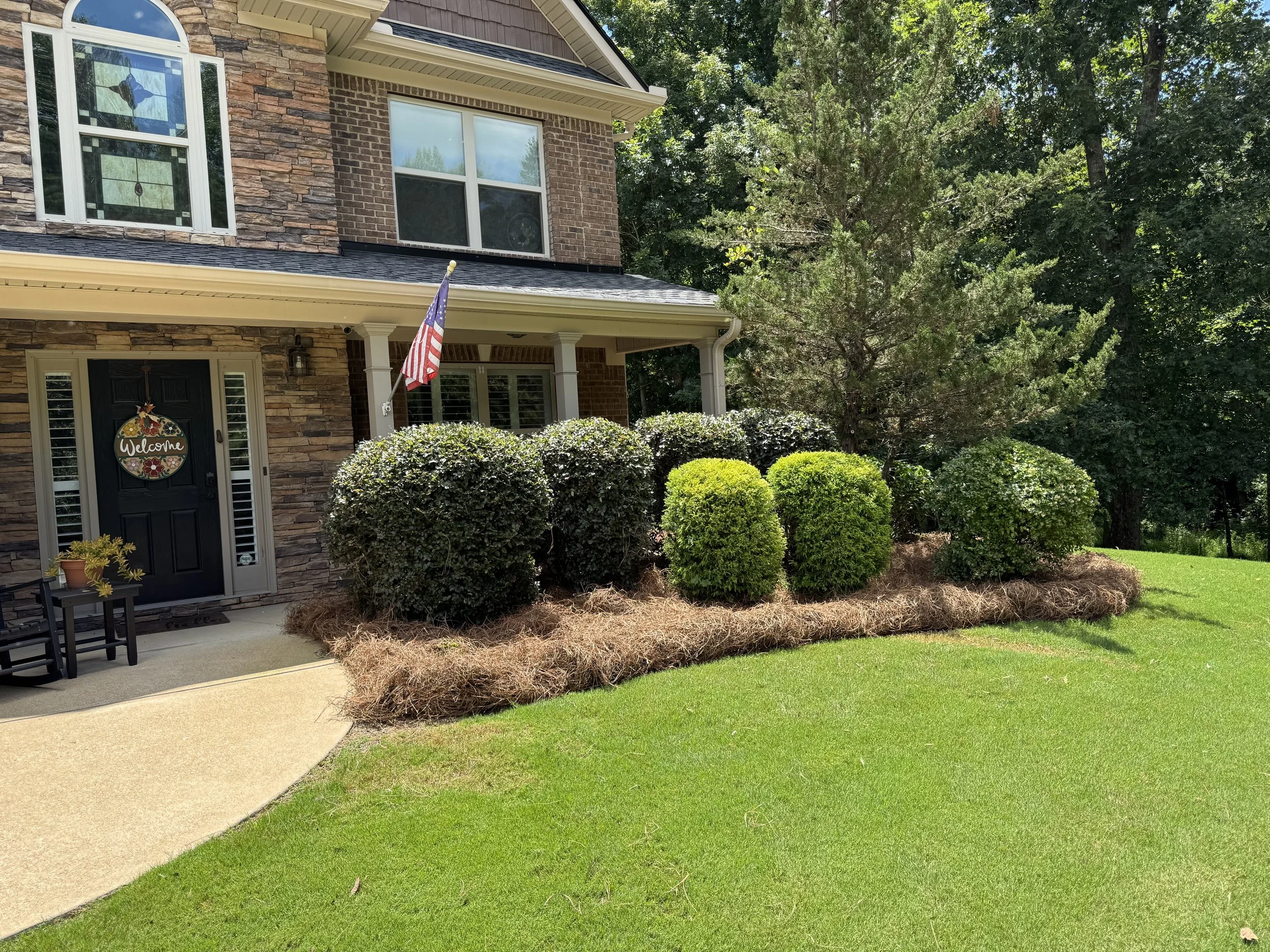 Professional pine straw installation and shrub trimming at a residential home in Dallas, GA.