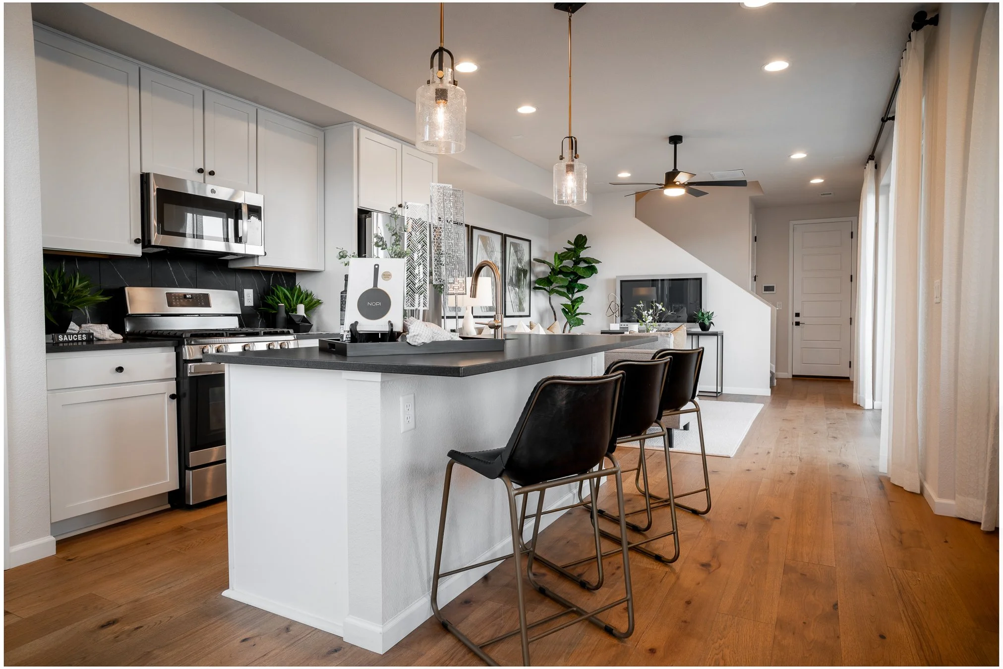 Kitchen breakfast bar with sleek black stools, pendant lighting, and a view of the staircase.