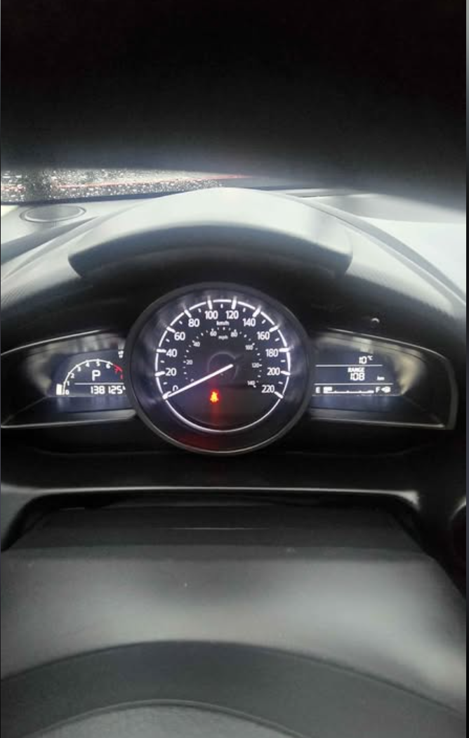 Car dashboard at night showing speedometer, fuel gauge, and temperature gauge with warning lights on.