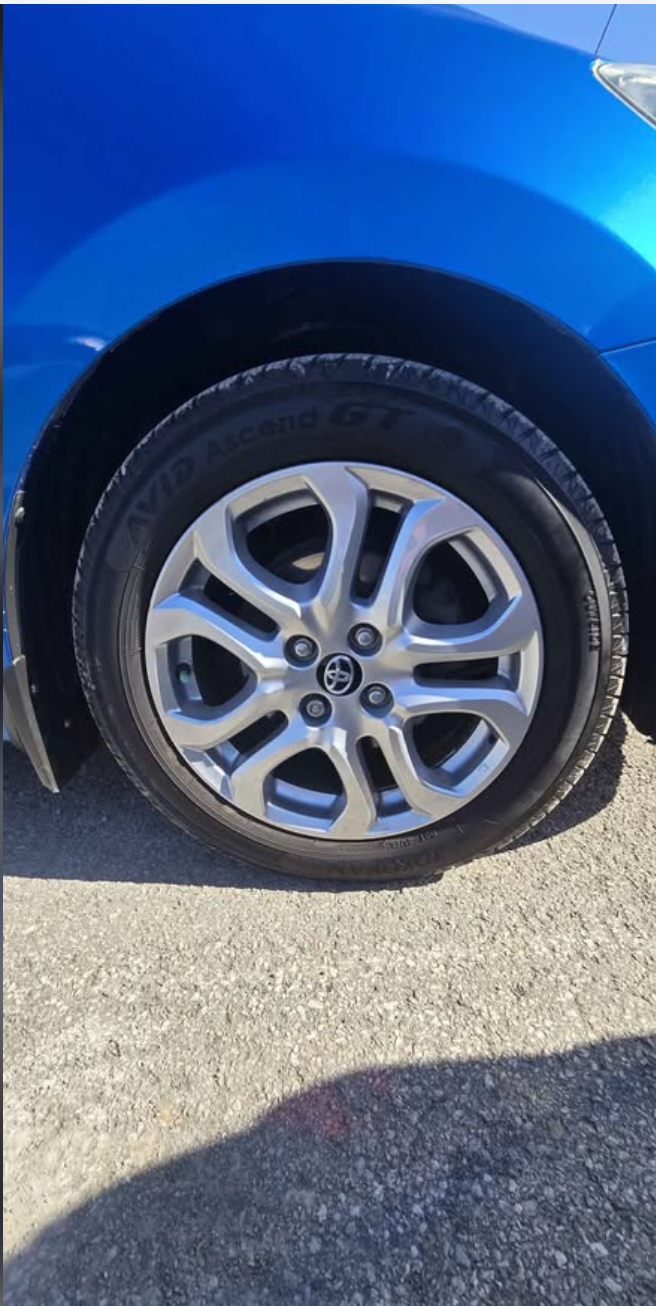front right wheel of a blue Toyota car showing the tire and alloy rim.