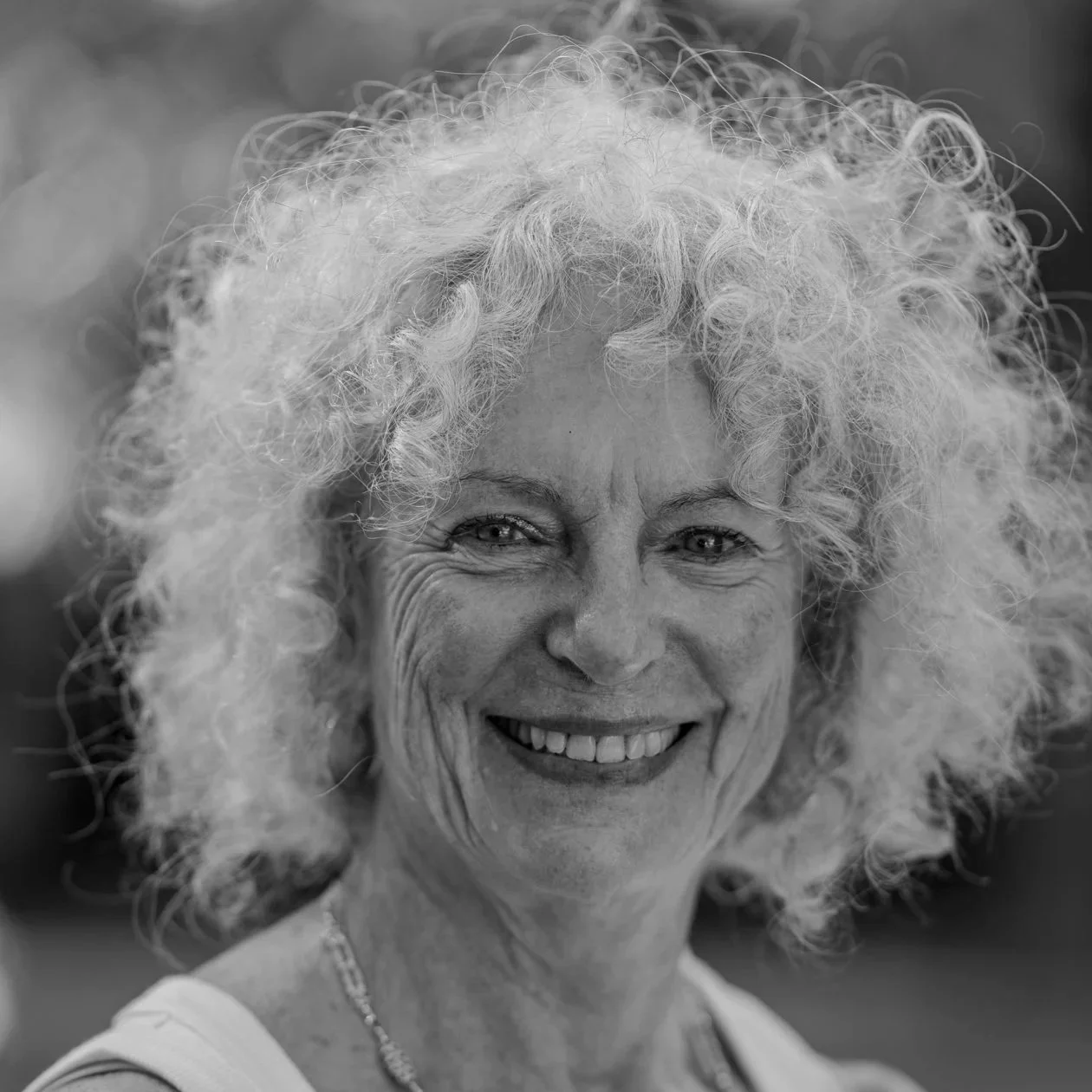 Black and white photo of silver frizzy haired woman smiling at camera
