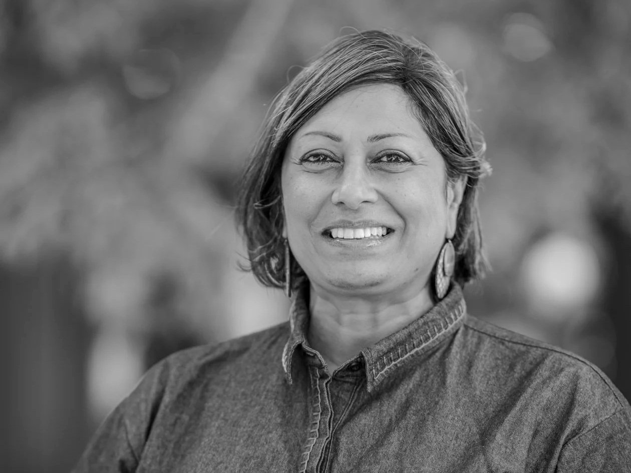 Black and white photo of woman with dark haired bob haircut smiling at camera wearing open necked shirt