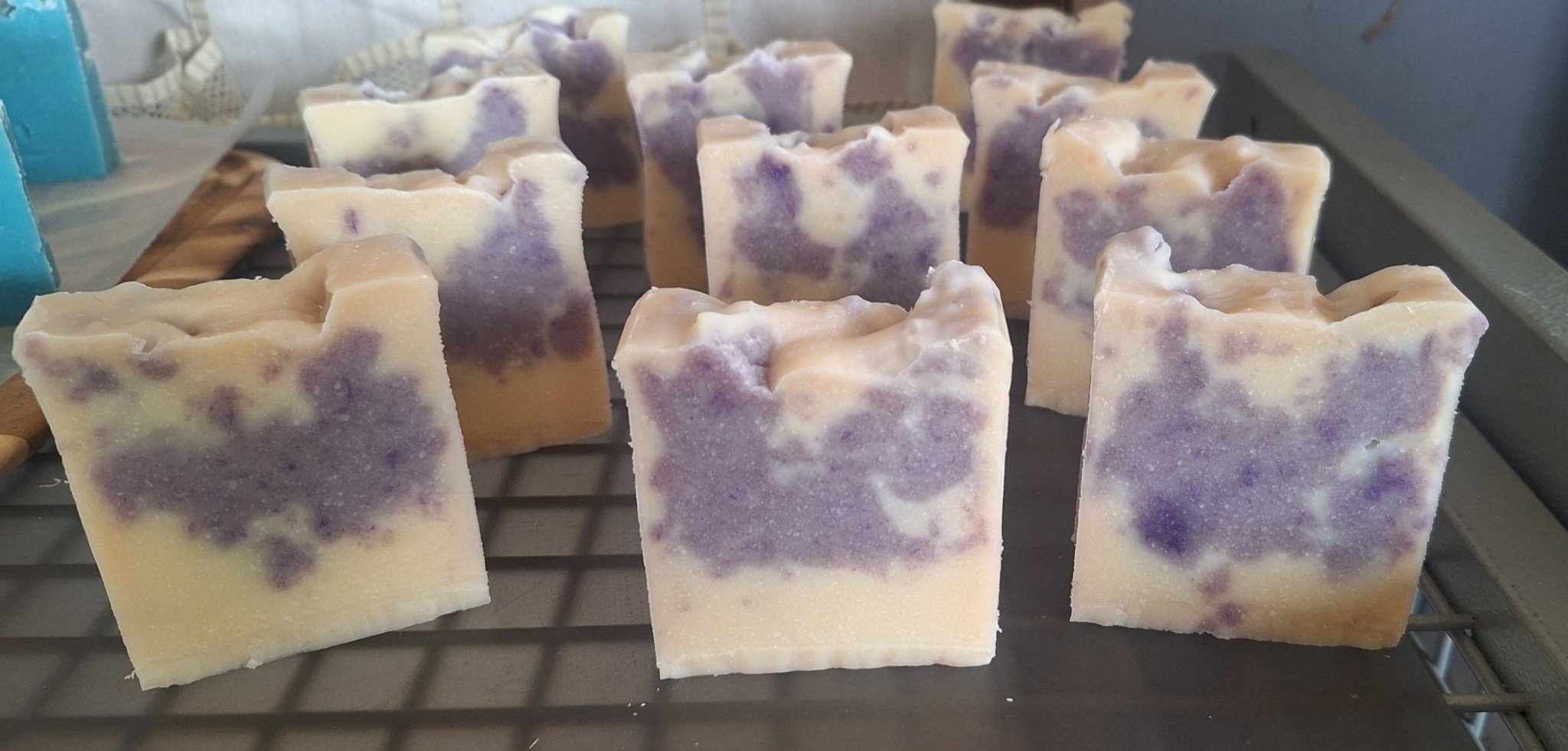 Several handmade soap bars with purple and white marbled pattern drying on a wire rack.