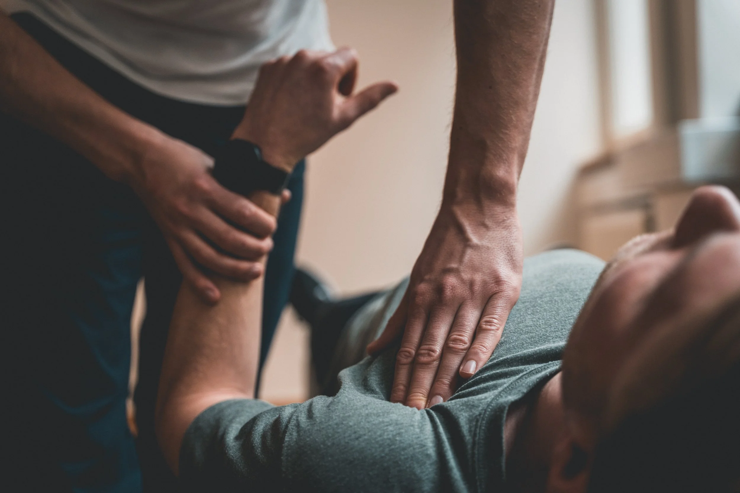 A person providing chest compressions during CPR on an unconscious individual lying on a flat surface.
