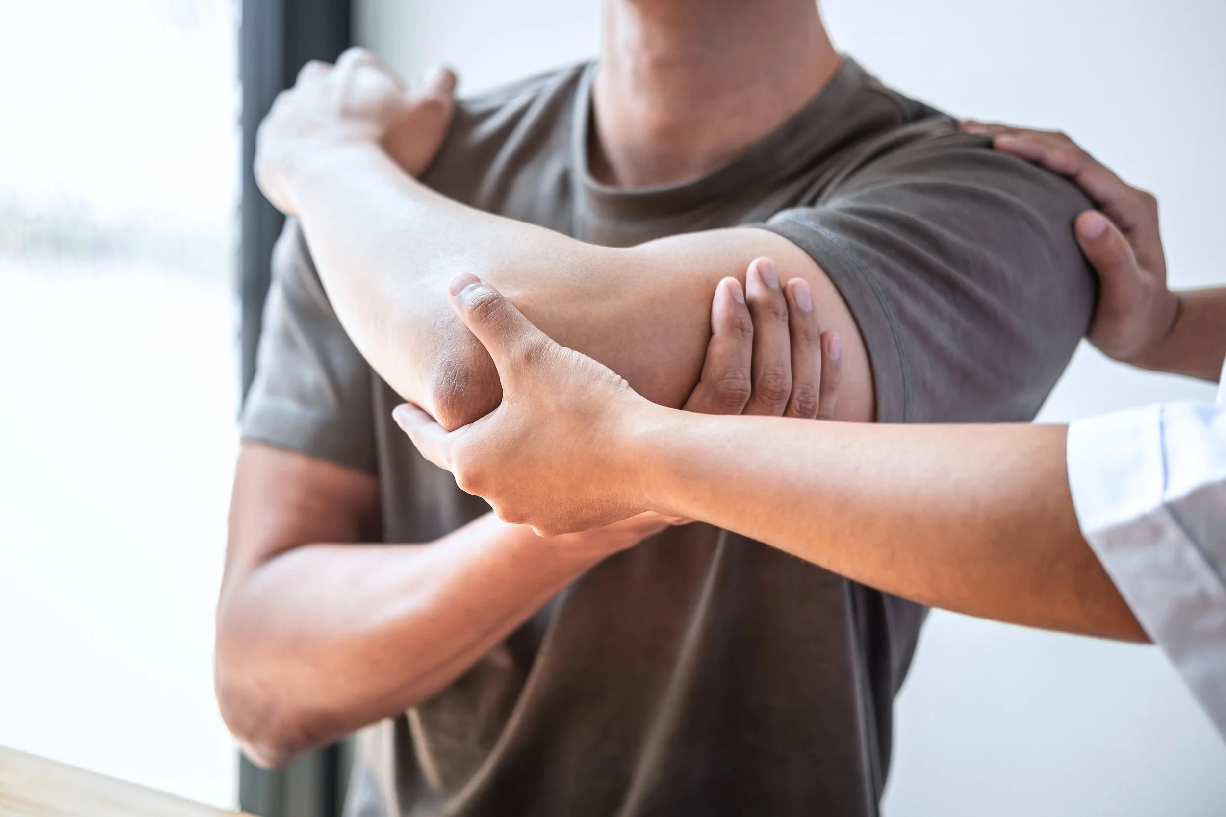 Medical professional performing a physical assessment of a patient's arm by gently stretching and examining the elbow.