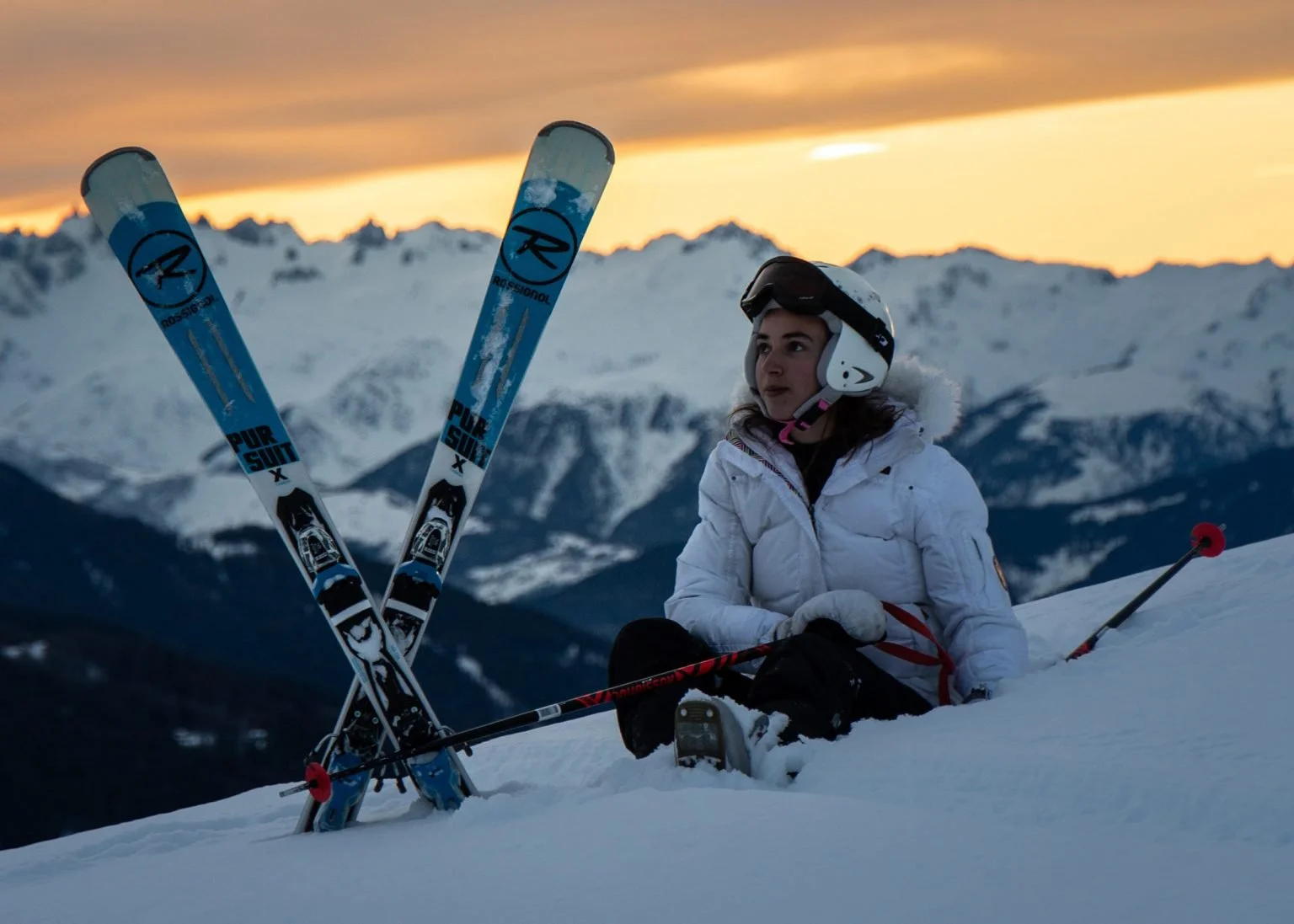 Skier at Hakuba sitting with skis crossed and stuck into ground