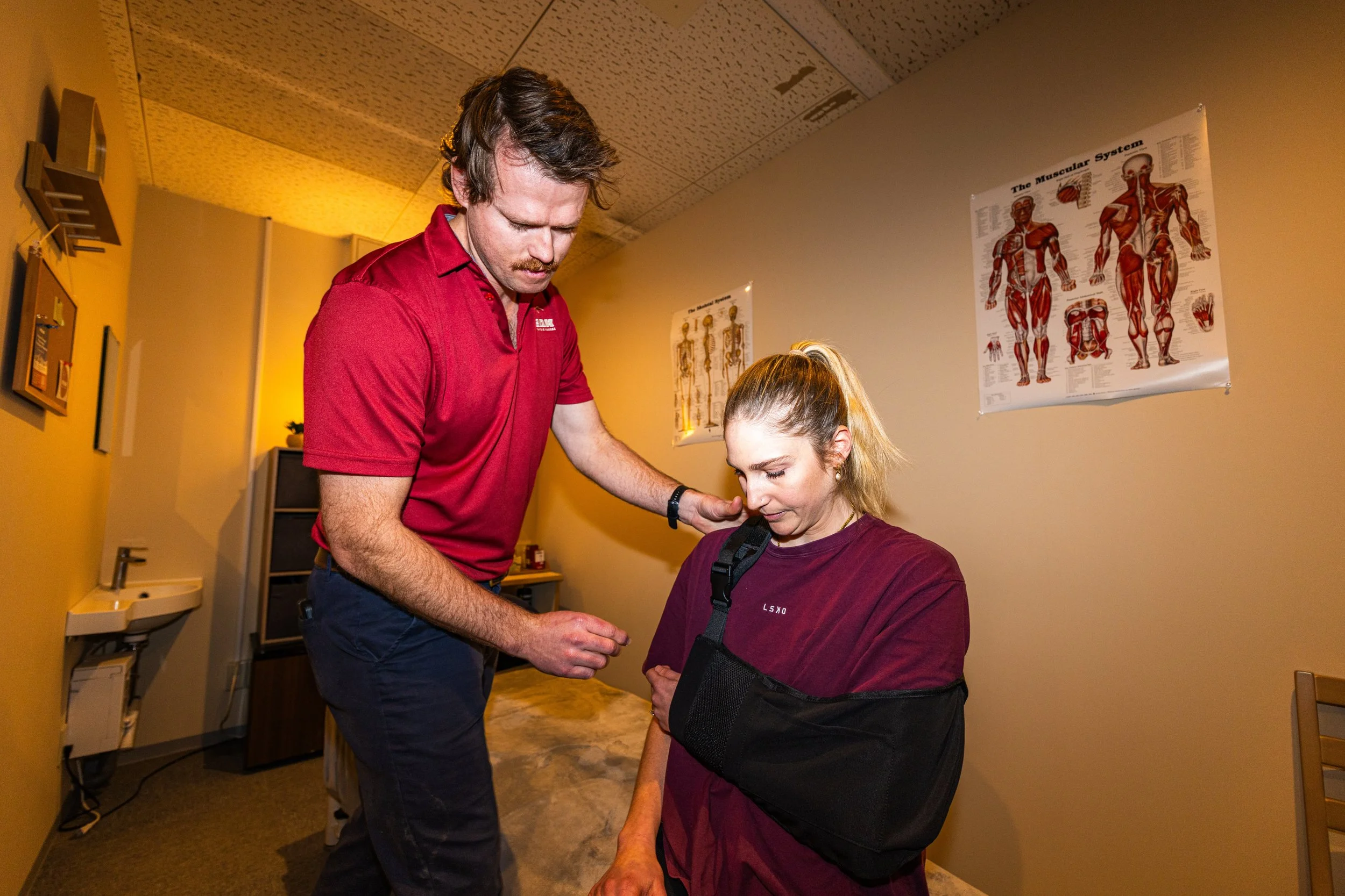 An injured person receives a shoulder sling from Peak Sports Physio Hakuba