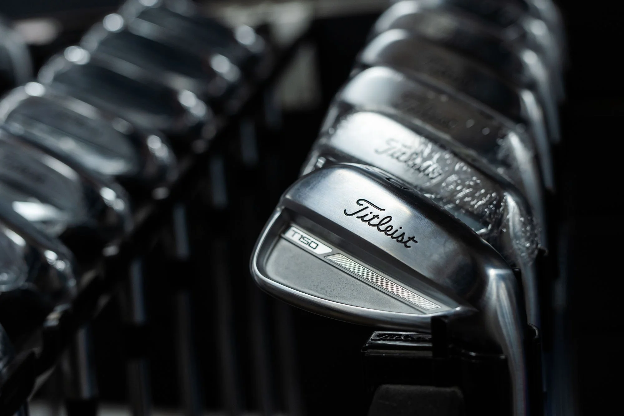 Close-up of a silver Titleist golf club lying among other golf clubs in a golf bag.