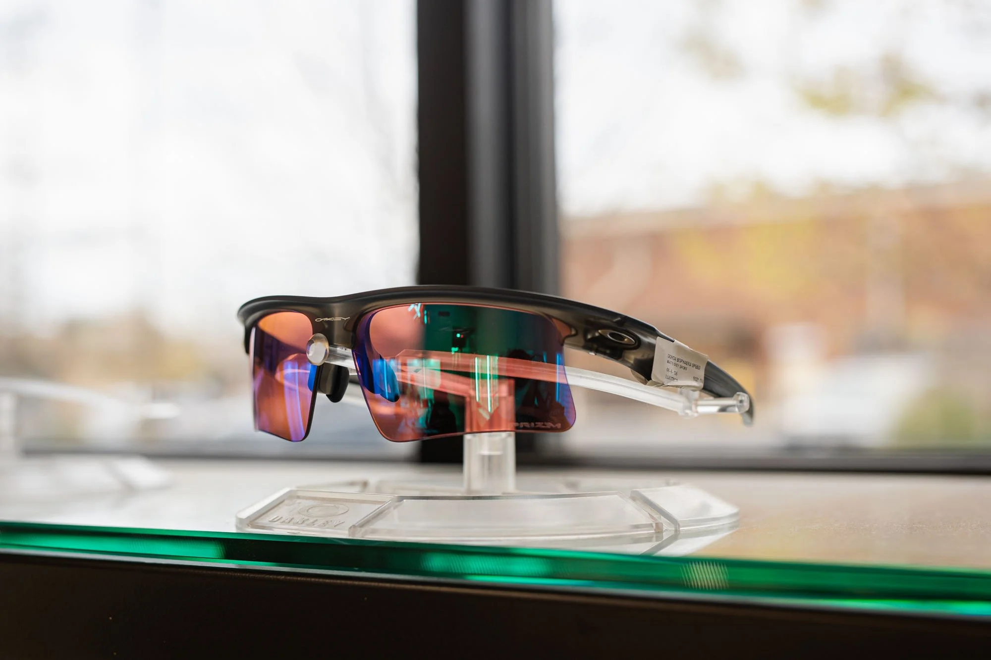 Sports sunglasses with mirrored lenses displayed on a white stand in a store.
